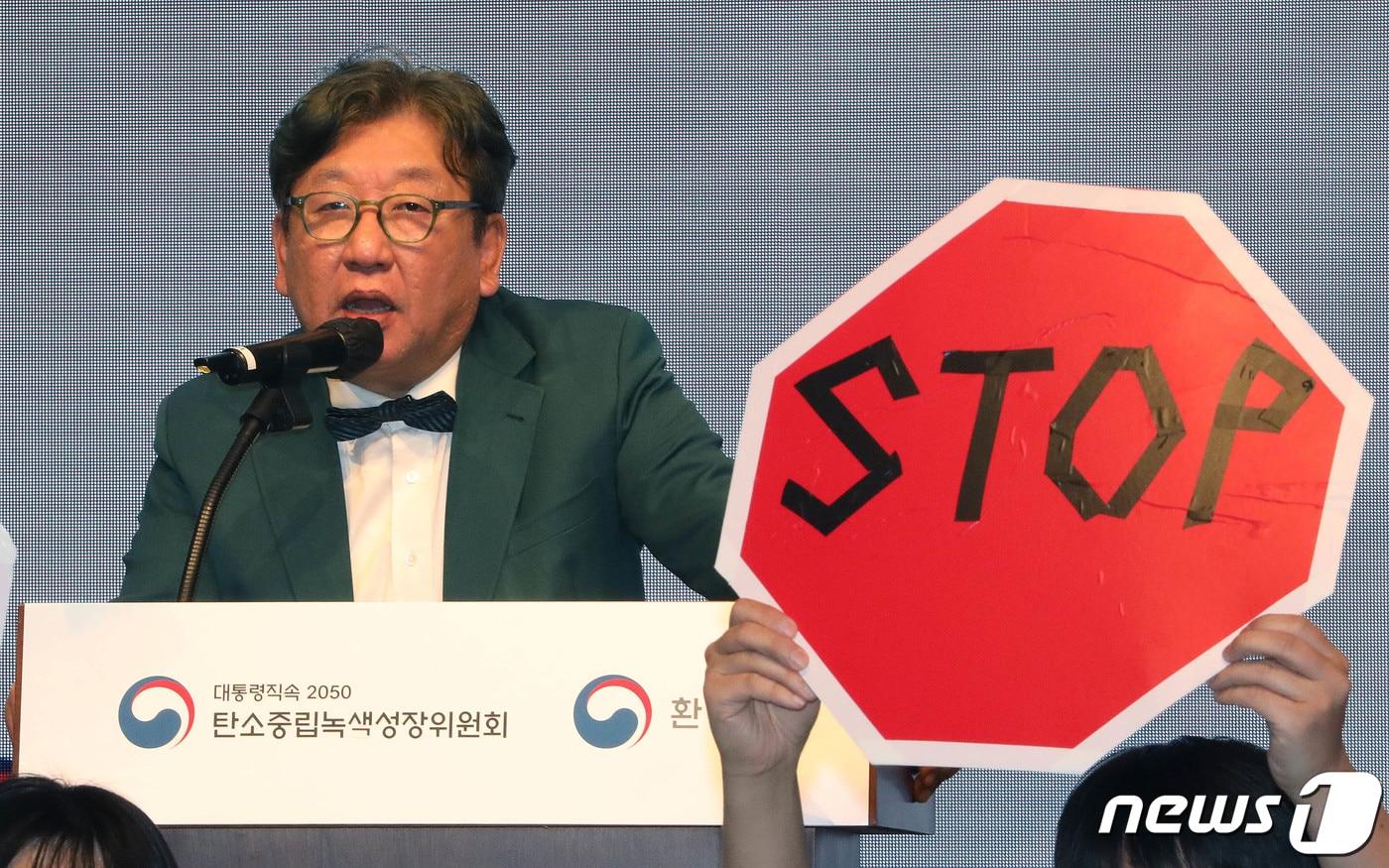 본문 이미지 - 김상협 탄소중립녹색성장위원장이 22일 서울 강남구 한국과학기술회관에서 열린 국가탄소중립 녹색성장 기본계획 수립 등에 대한 공청회에서 발언하고 있는 가운데 환경단체 회원들이 기본계획 철회를 촉구하며 피켓 시위를 하고 있다. 2023.3.22/뉴스1 ⓒ News1 박세연 기자