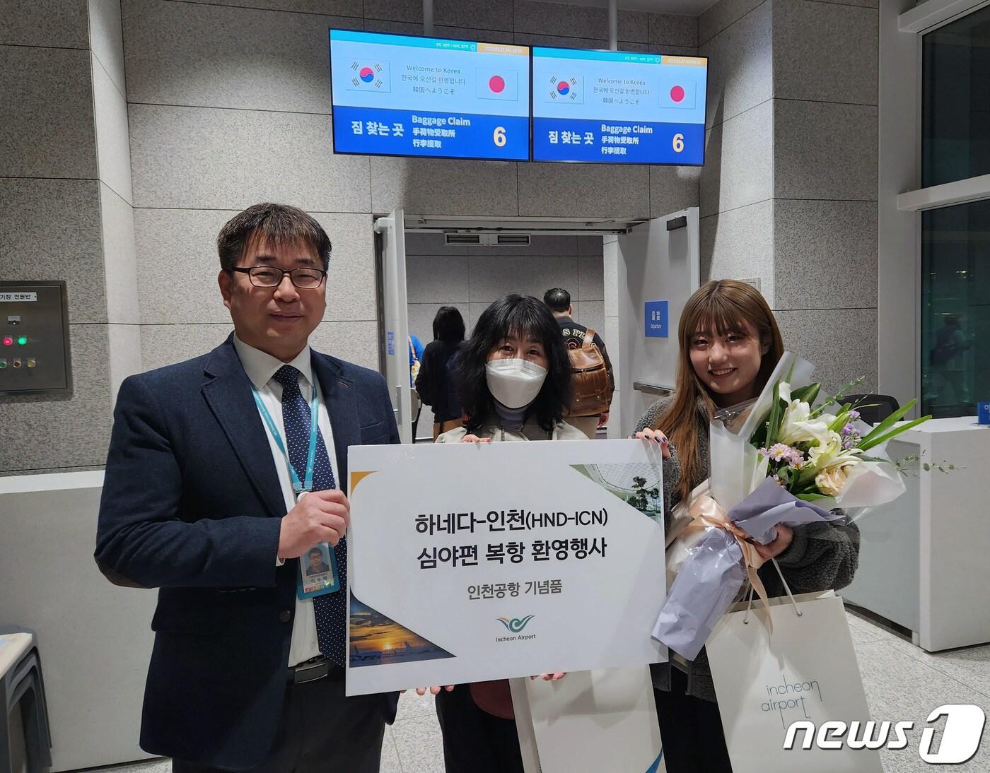 본문 이미지 - 27일 인천공항 제2여객터미널에서 열린 ‘하네다-인천 심야편 복항 환영 행사’에서 이수태 인천국제공항공사 항공마케팅팀장과 일본인 여객들이 기념사진을 찍고 있다. 인천국제공항공사는 이날부터 대한항공의 하네다-인천 심야정기편 운항이 재개되었다고 밝혔다. 2020년 3월 5일에 코로나19 여파로 중단된 이후 만 3년만이다. (인천공항공사 제공) 2023.3.27/뉴스1