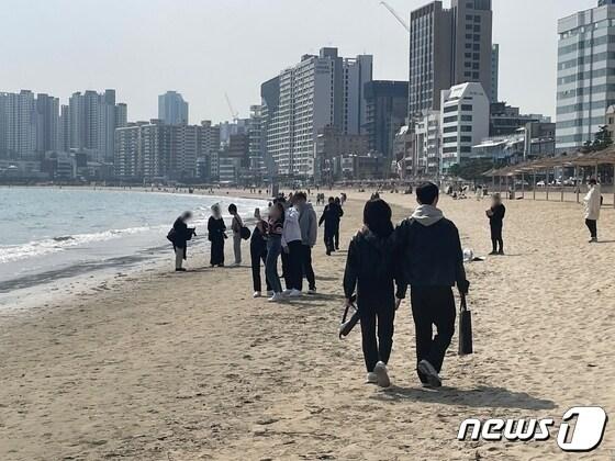본문 이미지 -  4일 오후 2시쯤 부산 수영구 광안리해수욕장 백사장에서 나들이객들이 사진을 찍고 모래 위를 걷고 있다.2023.3.4/뉴스1 강승우 기자