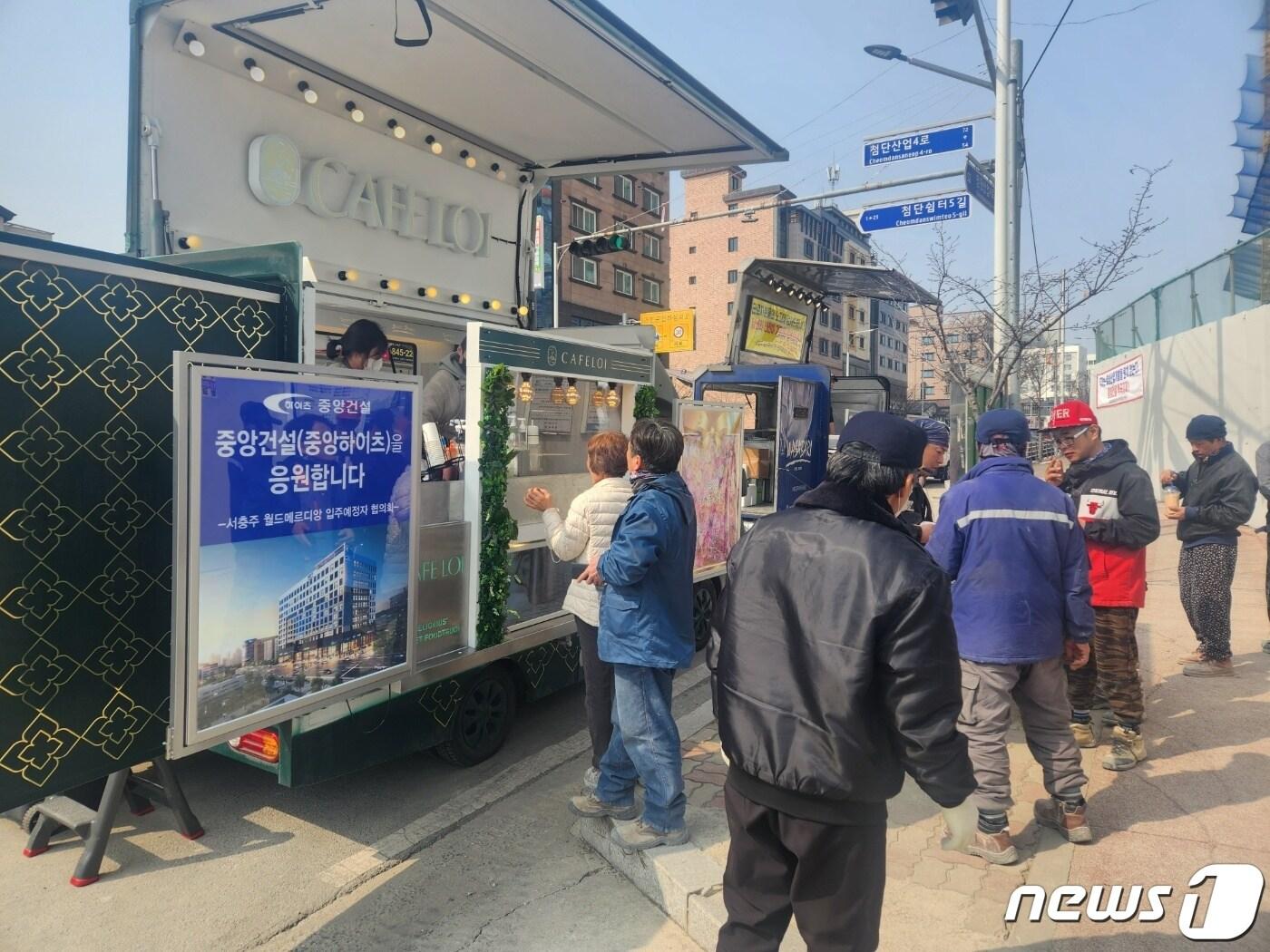 본문 이미지 - 7일 충북 충주시 서충주신도시 월드메르디앙 아파트 공사현장 근로자들이 입주예정자협의회가 준비한 푸드트럭에서 음료와 핫도그를 받고 있다.(독자 제공)2023.3.7/뉴스1