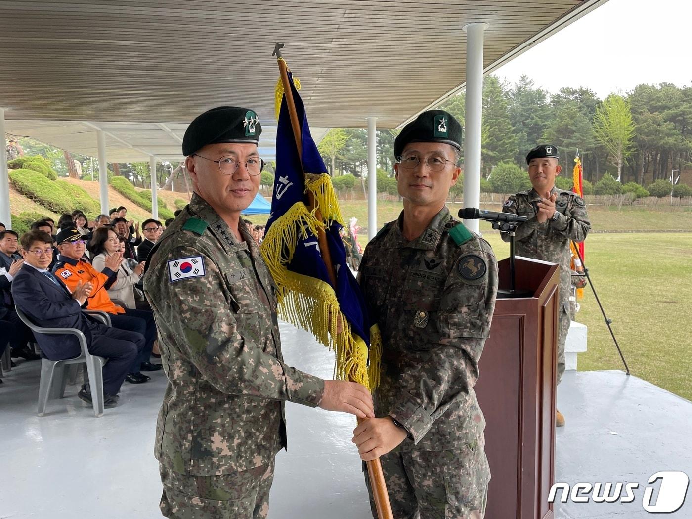 본문 이미지 - 20일 육군 제9보병사단 사령부에서 열린 사단장 이취임식에서 1군단장 강호필 장군(왼쪽)이 신임 사단장 정광웅 장군(오른쪽)에게 부대기를 이양하고 있다. (육군9사단 제공)