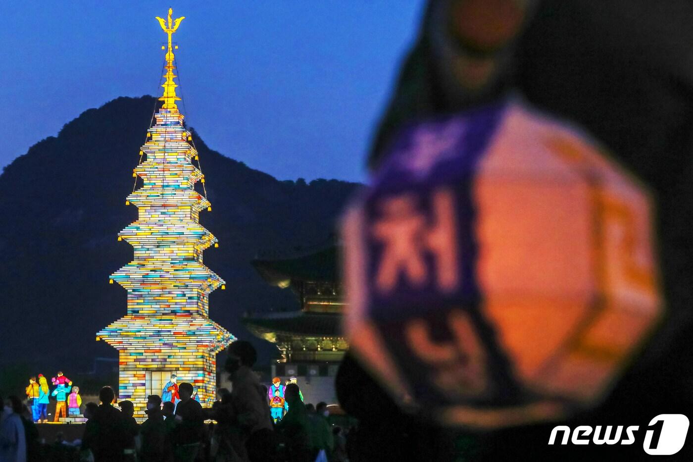 본문 이미지 - 26일 오후 서울 종로구 광화문광장에서 열린 '2023 부처님오신날 봉축점등식'에서 참석자들이 철물 구조와 한지 공예로 만든 20m 높이의 수마노탑 주변 탑돌이를 하고 있다. 2023.4.27/뉴스1 ⓒ News1 민경석 기자