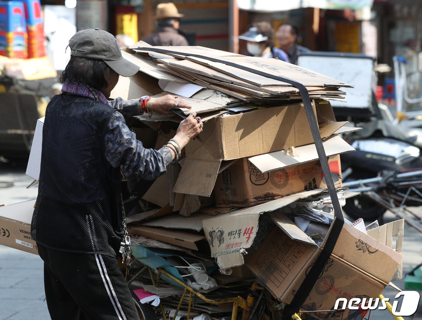 본문 이미지 - 서울의 고물상 앞에서 한 노인이 리어카에 쌓인 폐지를 정리하고 있다. ⓒ 뉴스1 신웅수 기자
