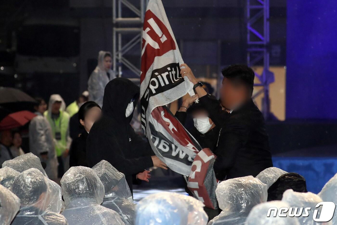 본문 이미지 - 박양우 광주비엔날레 대표이사가 6일 오후 광주 북구 비엔날레 전시관 광장에서 열린 '제14회 광주비엔날레 개막식'에서 '박서보 예술상' 발표하는 가운데 한 에술인이 신설된 예술상을 거부하는 현수막을 펼치려다 제지당하고 있다. 2023.4.6/뉴스1 ⓒ News1 황기선 기자