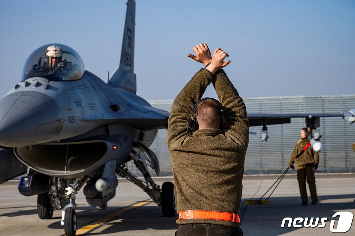 본문 이미지 - 루마니아 페테스티 인근 공군기지에서 미 공군 비행사가 F-16 전투기에 신호를 보내고 있다. ⓒ 로이터=뉴스1 ⓒ News1 권진영 기자