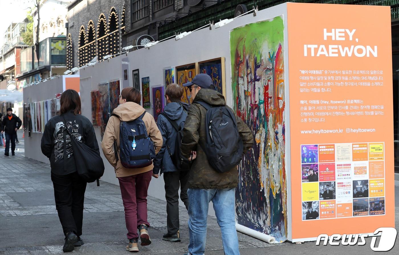 사진은 서울 용산구 이태원 세계음식문화거리에서 열린 거리전시회 '헤이, 이태원'을 찾은 외국인 관광객이 전시된 작품을 살펴보고 있다. 2023.4.9/뉴스1 ⓒ News1  