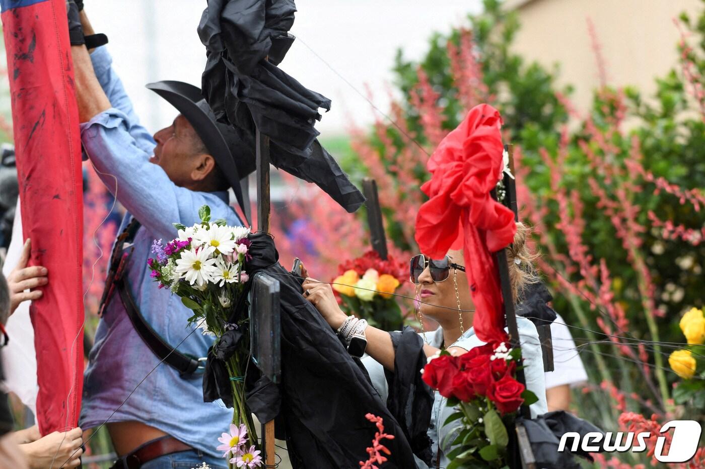 댈러스 출신의 한 벽화가 2023년 5월7일(현지시간) 미 텍사스주 댈러스 외곽 앨런 프리미엄 아웃렛에서 총기 난사 사건으로 목숨을 잃은 사람들을 기리기 위해 기념비를 세우고 있는 모습. ⓒ 로이터=뉴스1 ⓒ News1 김현 특파원