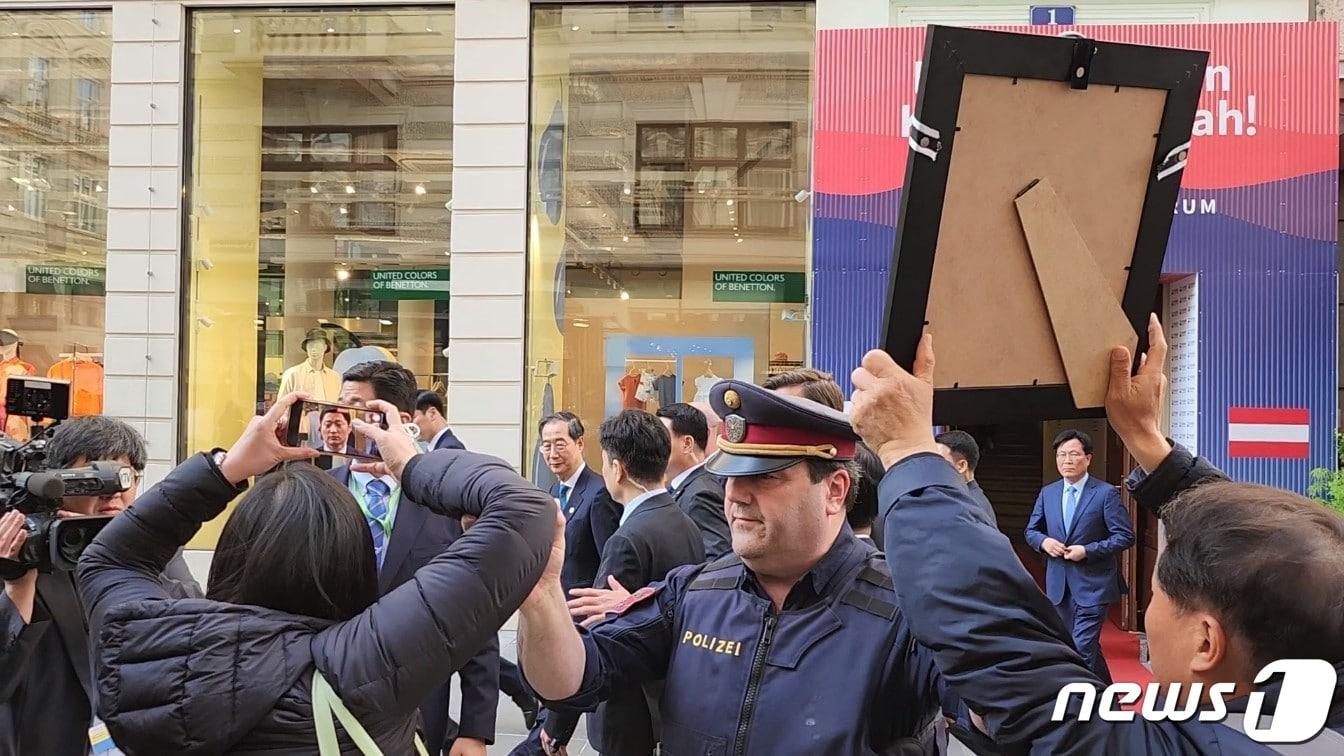 본문 이미지 - 한덕수 국무총리가 9일&#40;현지시간&#41; 주 오스트리아 한국문화원 앞에서 시위를 벌이고 있는 이태원 참사 희생자 고&#40;故&#41; 김인홍씨&#40;25&#41; 유가족 앞을 지나가고 있다./