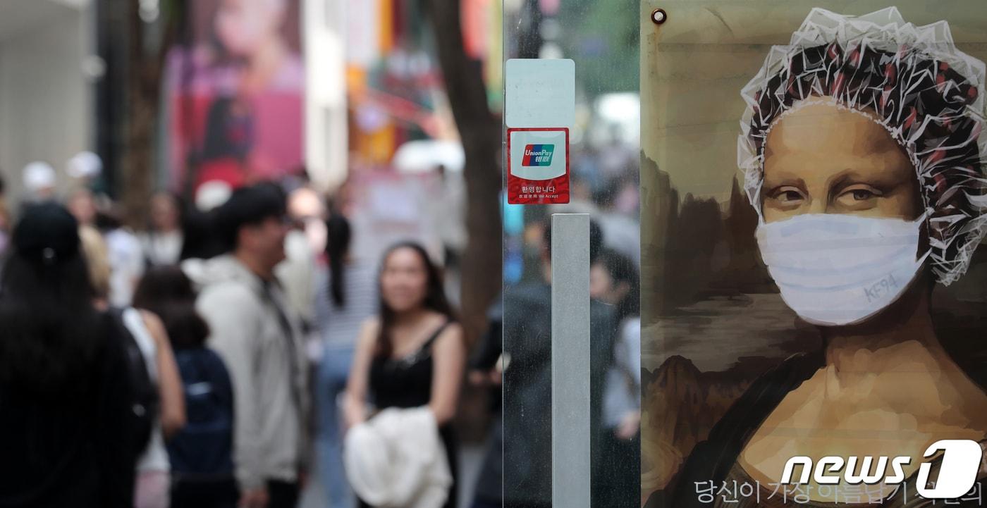 본문 이미지 - 정부가 코로나19 확진자의 7일 격리 의무를 완전히 해제할 것으로 알려진 10일 서울 중구 명동거리의 한 헤어샵 광고에 마스크가 보이고 있다. 윤석열 대통령은 내일 9개월 만에 코로나19 중앙재난안전대책본부 회의를 주재하고, 방역 완화 방안을 발표 할 예정이다. 2023.5.10/뉴스1 ⓒ News1 이승배 기자