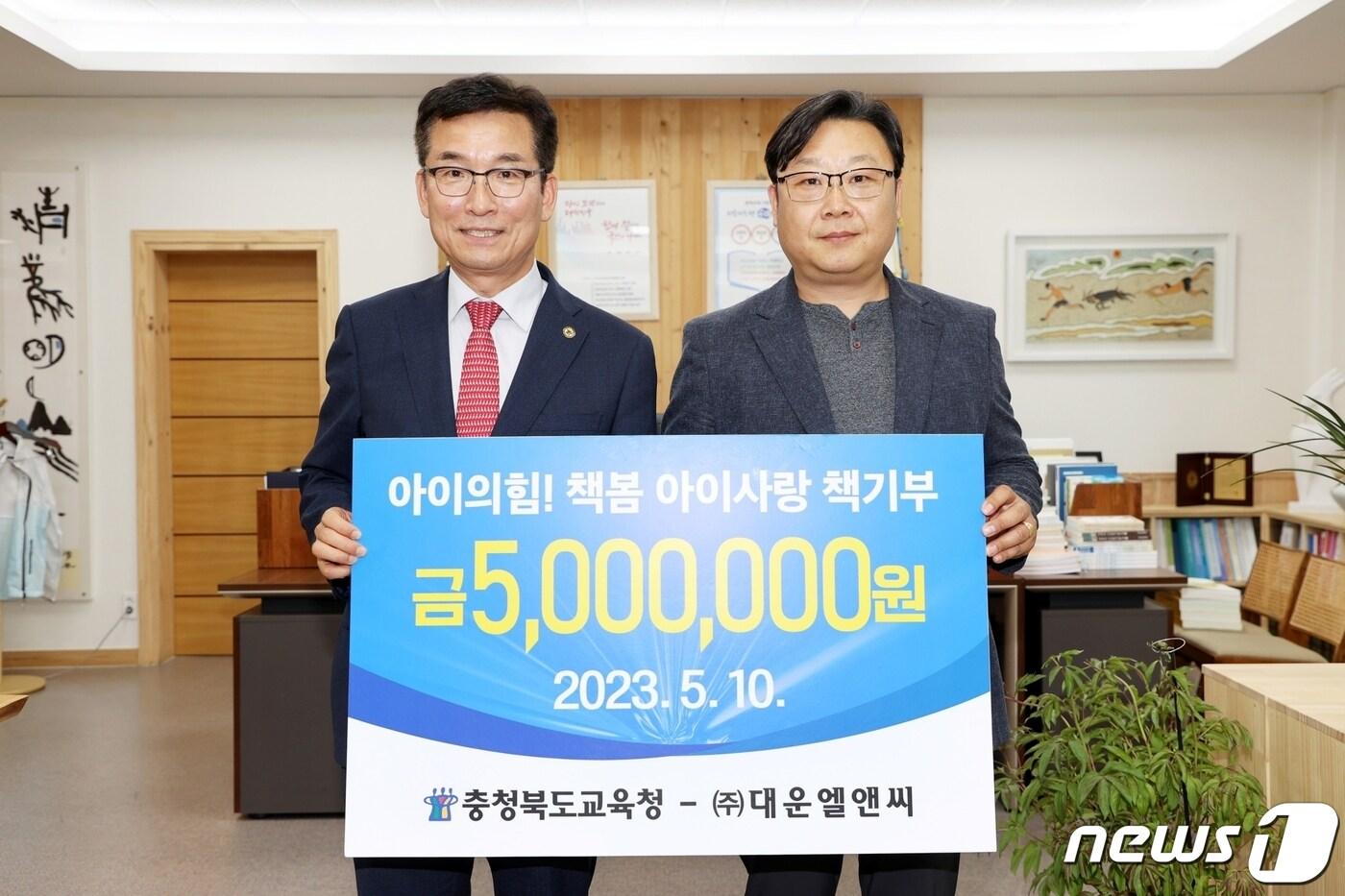본문 이미지 - ㈜대운엘앤씨(대표 송재운·오른쪽)가 충북교육청이 추진하는 '아이의 힘 책봄 아이사랑 책 기부' 운동에 동참해 청주고등학교 도서구매비 500만원을 충북교육청에 기탁했다.(충북교육청 제공)/ 뉴스1