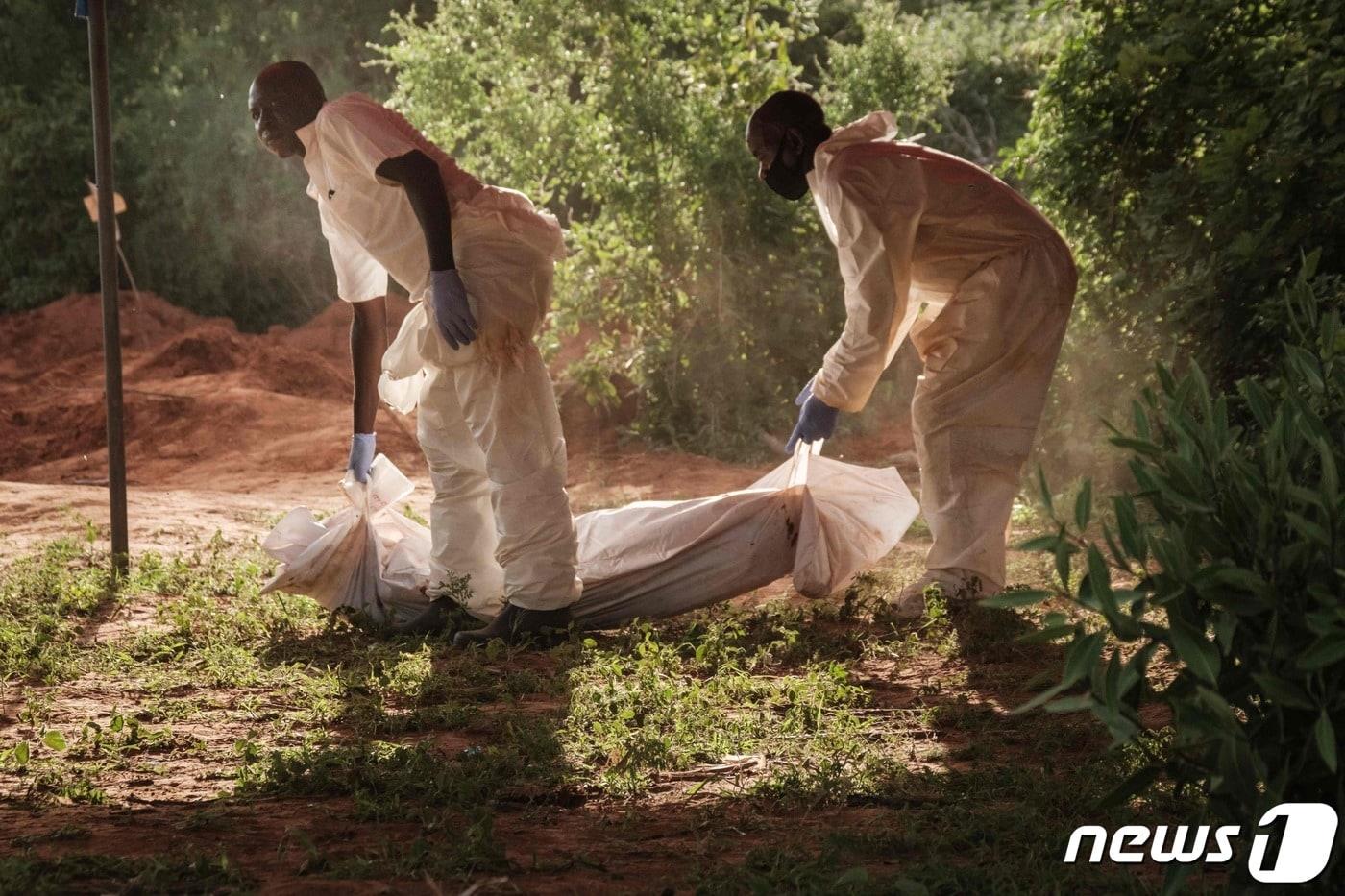 케냐 남동부 해안도시 말린디 인근 샤카홀라 숲에서 흰색 방호복을 입은 두 남성이 시신 1구를 수습하고 있다. 2023.4.25 ⓒ AFP=뉴스1 ⓒ News1 정윤미 기자