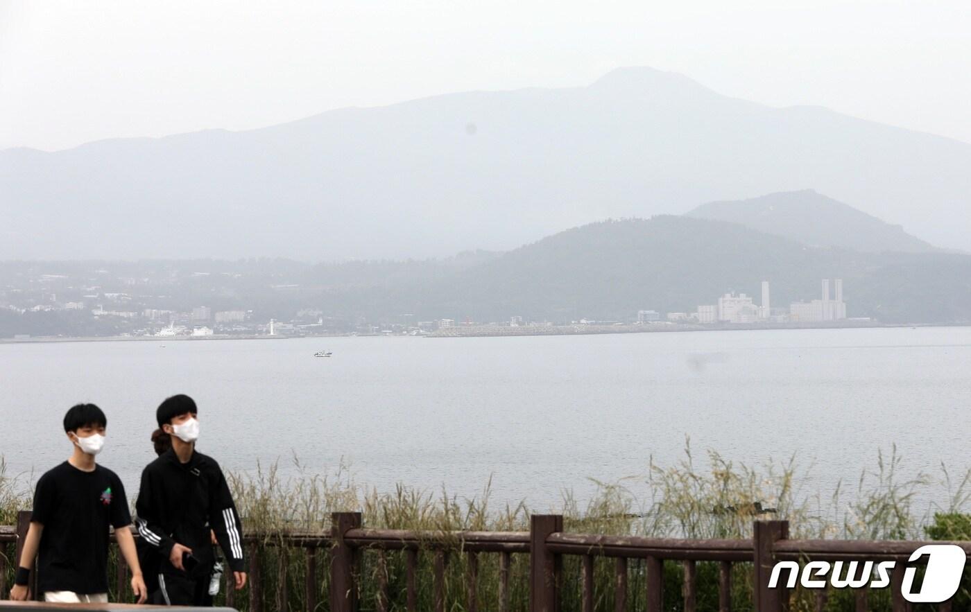 본문 이미지 - 중국발 황사의 영향으로 전국의 미세먼지 농도가 나쁨 수준을 보이고 있는 22일 오후 제주 서귀포시 대정읍 송악산을 찾은 마스크를 착용한 관광객 뒤로 한라산이 뿌옇게 보이고 있다. 2023.5.22/뉴스1 ⓒ News1 고동명 기자