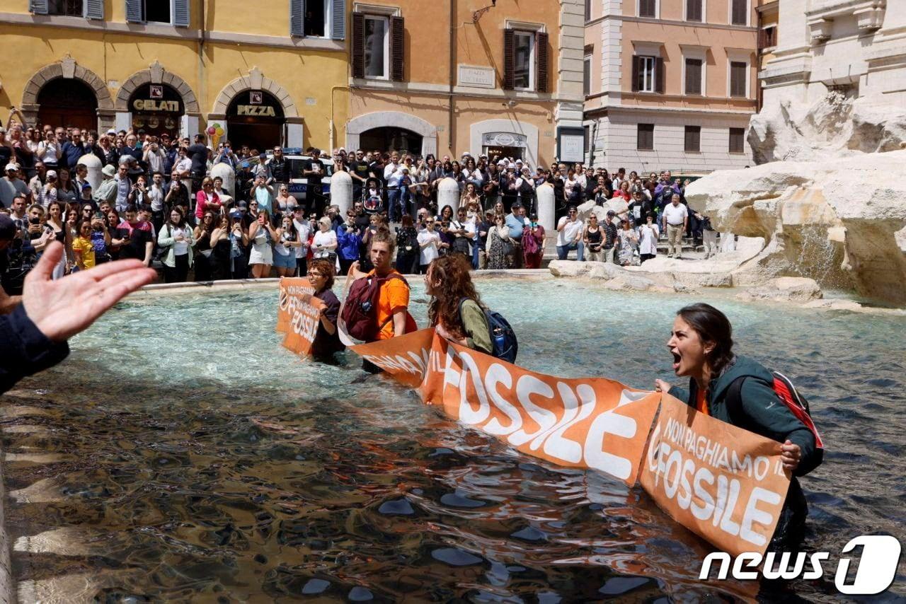 본문 이미지 - 환경단체 '울티마 제네라치오네'(이탈리아어로 '마지막 세대'라는 뜻) 활동가들은 21일(현지시간) 식물성 먹물을 트레비 분수에 부었다. 이들은 검게 변한 물 속에서 '화석연료는 안 된다'고 적힌 천을 든 채 "정부가 구체적인 조처를 취하기까지 얼마나 더 기다려야 하느냐＂고 규탄했다. 2023.05.21 ⓒ 로이터=뉴스1 ⓒ News1 김예슬 기자