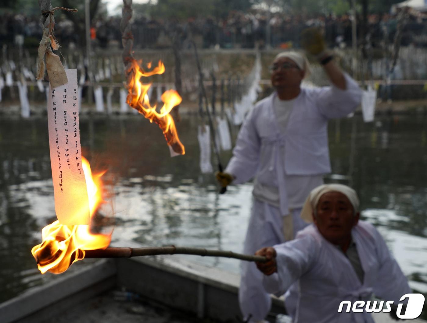 본문 이미지 - 5월27일 오후 경남 함안군 함안면 무진정에서 '함안 낙화놀이'가 열린 가운데 관계자가 소원이 적힌 한지에 불을 붙이고 있다. 경남 무형문화재 제33호인 함안 낙화놀이는 숯과 한지를 꼬아 만든 실 수천 개를 줄에 매달아 해질녘 불을 붙이는 민속놀이다. 2023.5.27/뉴스1 ⓒ News1 윤일지 기자