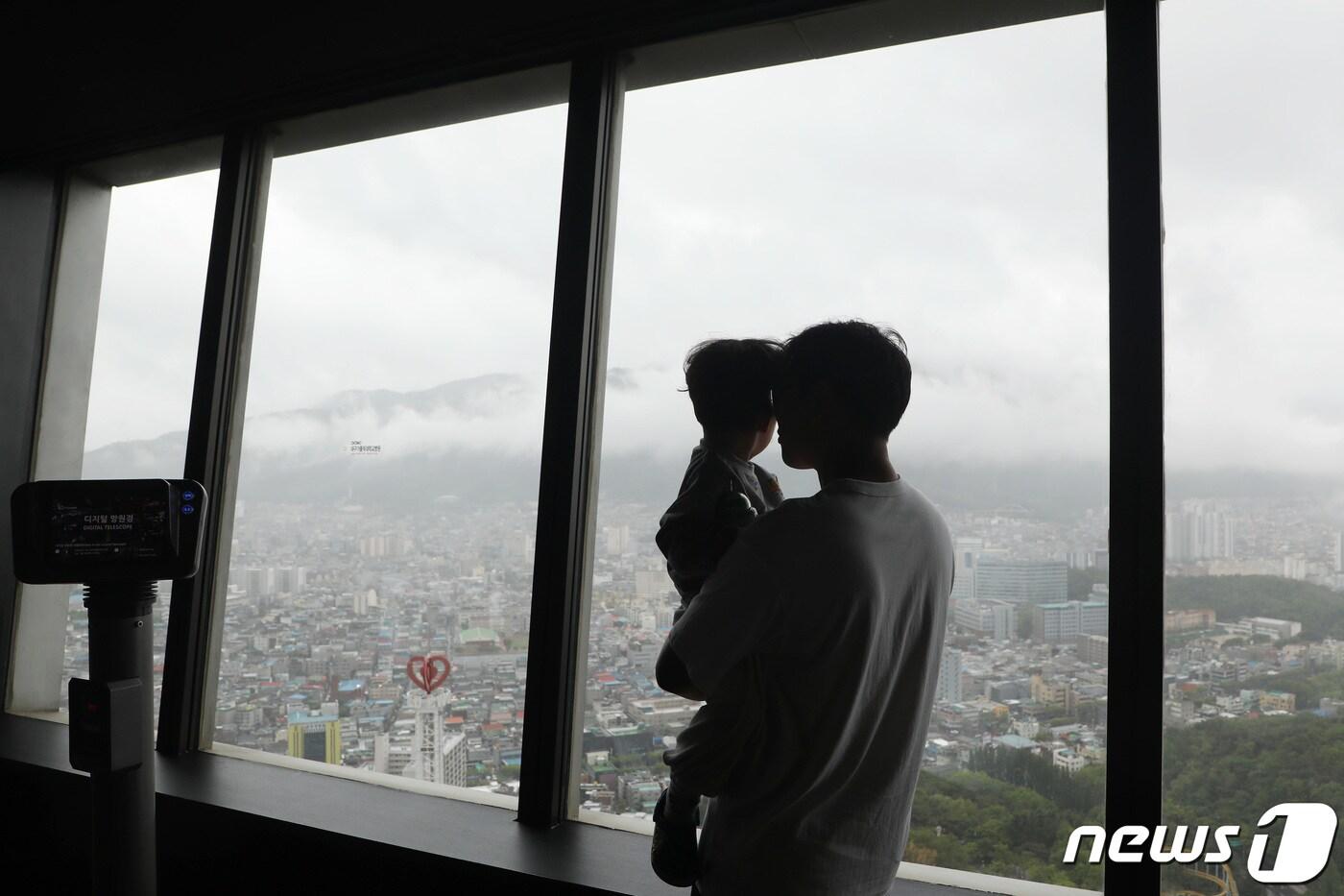 본문 이미지 - 어린이날인 5일 전국에 많은 비가 내리는 가운데 대구 달서구 이월드를 찾은 가족이 83타워 실내전망대에서 비 내리는 도심을 하염없이 바라보고 있다. 2023.5.5/뉴스1 ⓒ News1 공정식 기자