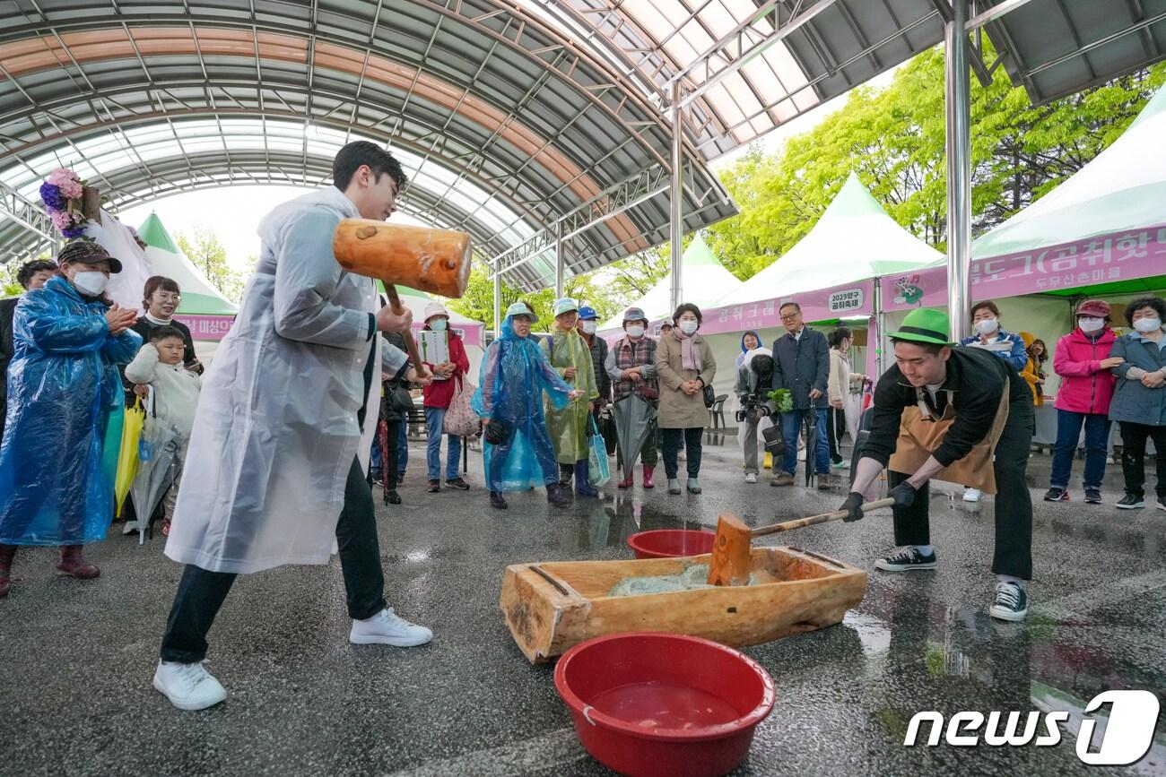 본문 이미지 - 연휴 이틀째인 6일 강원 양구군 서천 레포츠공원 일원에서 열리는 곰취축제장에 한 관광객이 우비를 입고 곰취 떡메치기 체험을 하고 있다.(뉴스1 DB)
