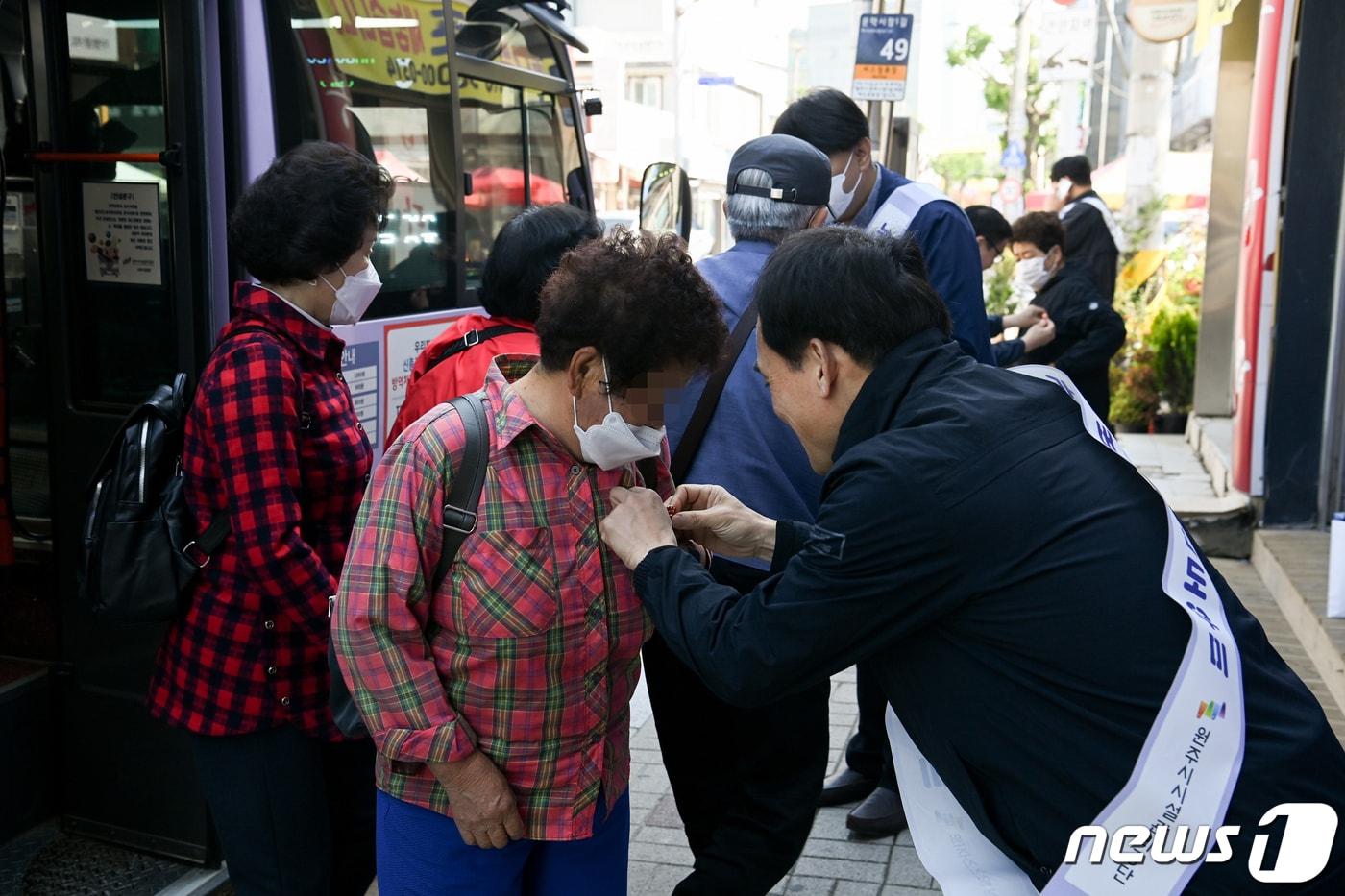 본문 이미지 - 강원 원주시시설관리공단 교통사업부 누리버스팀이 ‘제51회 어버이날’을 맞은 8일 원주 문막읍 누리버스 정류장에서 ‘카네이션 달아드리기 행사'를 진행하고 있다. (원주시시설관리공단 제공) 2023.5.8/뉴스1