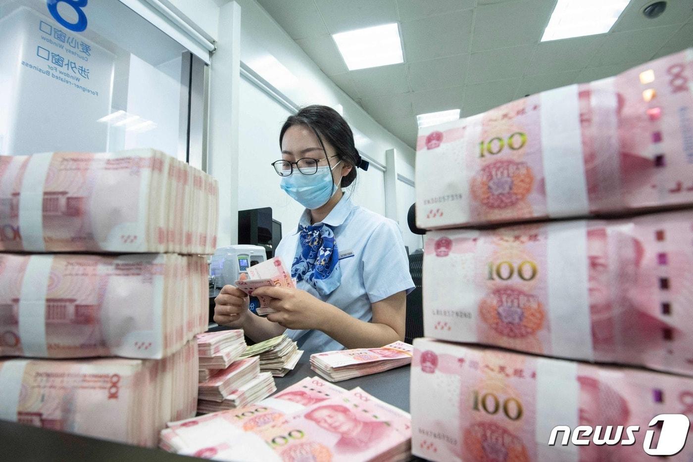 13일 중국 동부 장쑤성 난퉁의 한 은행 창구에서 은행 직원이 100위안짜리 지폐를 세고 있는 모습. 23.06.13 ⓒ AFP=뉴스1 ⓒ News1 김예슬 기자