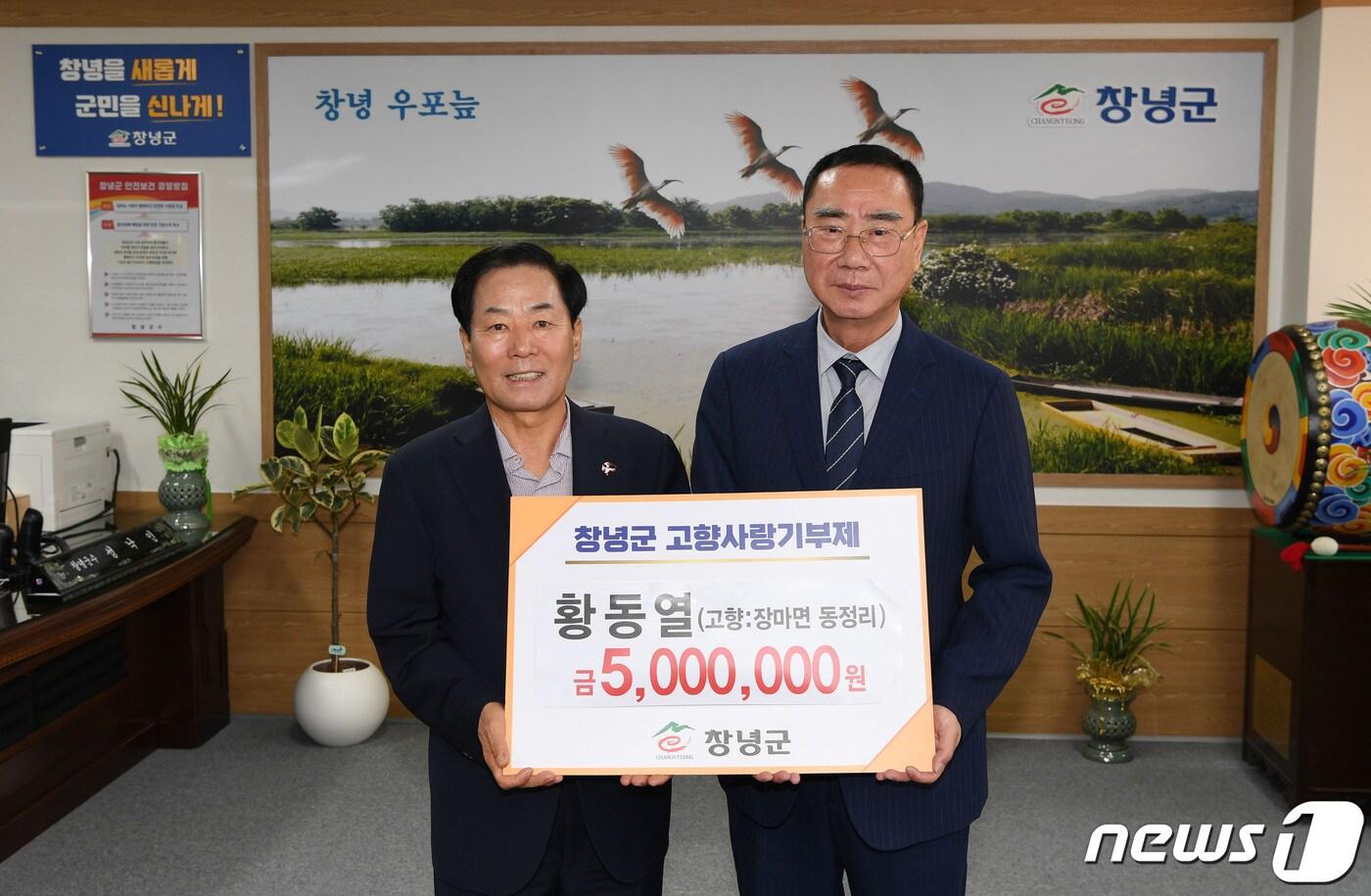 본문 이미지 - 창녕군 장마면 동정리 출신 황동열 씨(오른쪽)와 성낙인 창녕군수가 기념촬영을 하고 있다.(창녕군 제공)