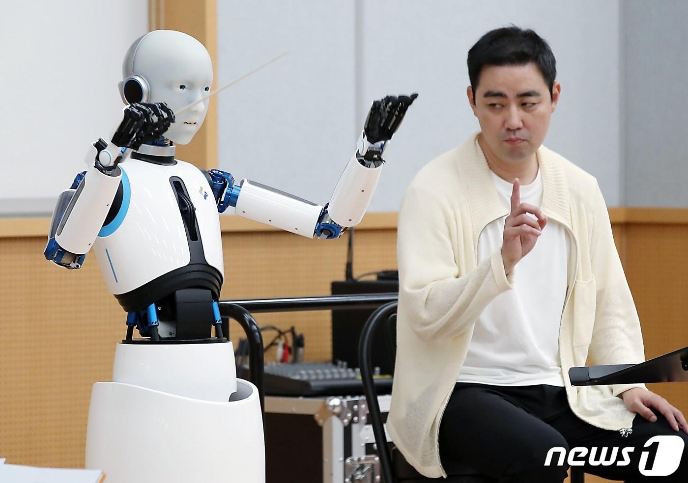 본문 이미지 - 최수열 지휘자(오른쪽)가 26일 오후 서울 중구 장충동 국립극장 해오름극장 관현악단 연습실에서 국내 최초 지휘하는 로봇 '에버 6'와 비얌바수렌 샤라브 작곡의 '깨어난 초원' 무대를 함께하고 있다.  2023.6.26/뉴스1 ⓒ News1 박정호 기자
