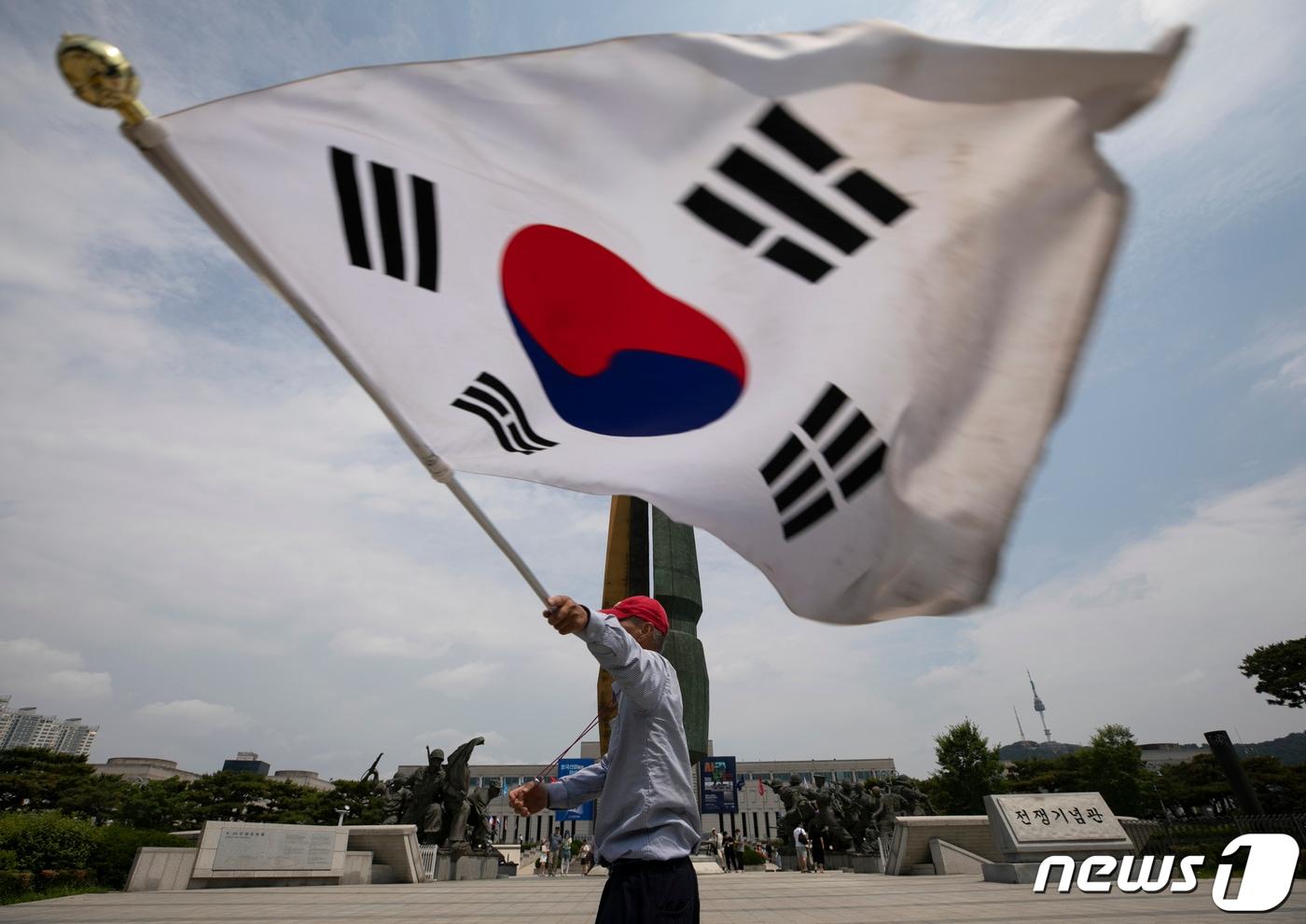 본문 이미지 - 제68회 현충일인 6일 오전 서울 용산구 전쟁기념관에서 한 시민이 애국가를 부르며 태극기를 흔들고 있다. 2023.6.6 ⓒ 뉴스1 신웅수 기자