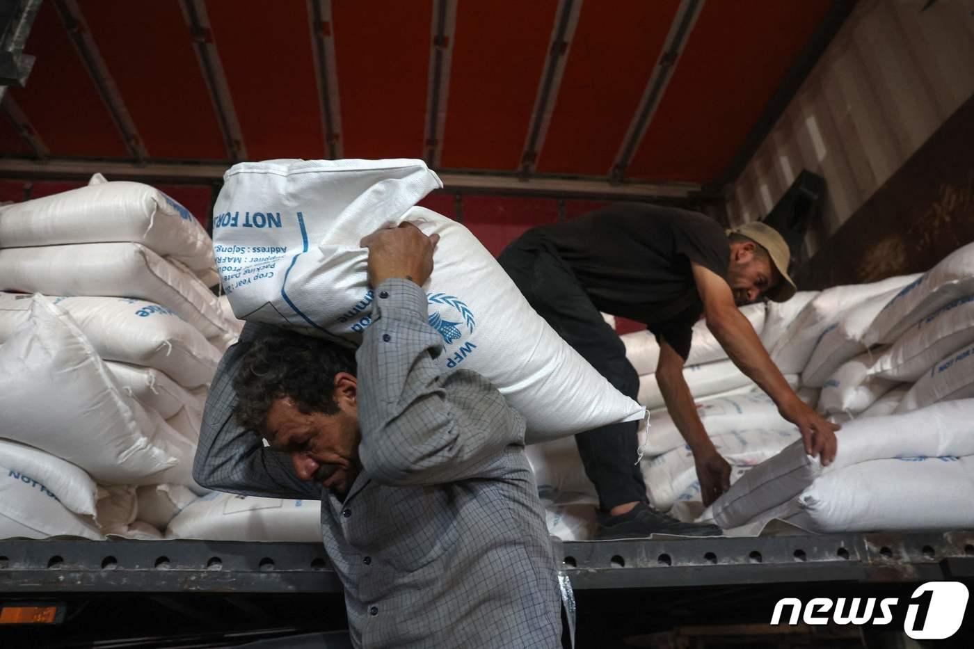 10일(현지시간) 튀르키예와 교차하는 시리아의 밥 알하와 국경 근처 창고에서 노동자들이 유엔에서 제공한 구호물품을 나르고 있다. 2023.07.10/ ⓒ AFP=뉴스1 ⓒ News1 권진영 기자