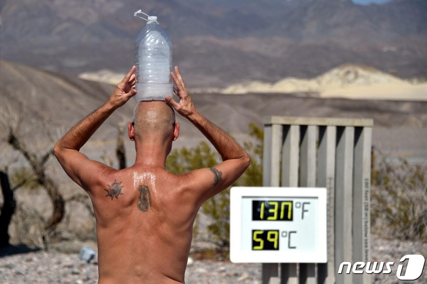 본문 이미지 - 한 남성이 얼음물을 담은 병을 머리에 이고 캘리포니아 데스밸리를 걷고 있다. 2020.8.17 ⓒ 로이터=뉴스1 ⓒ News1 강민경 기자