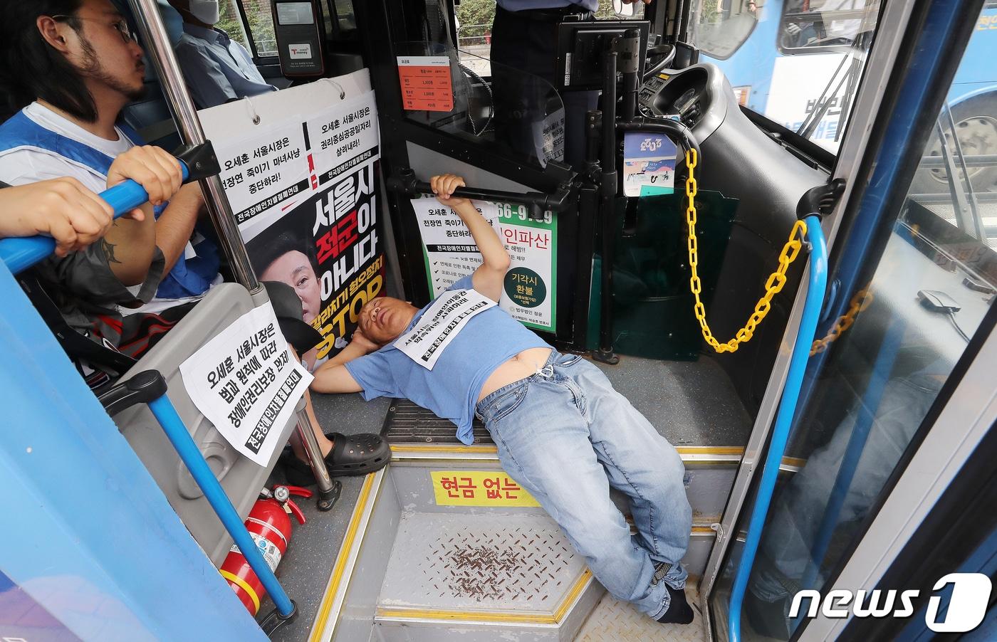 본문 이미지 - 전국장애인차별철폐연대(전장연) 회원들이 17일 오후 서울 종로구 혜화동로터리 버스 정류장에서 전장연 탄압 중단을 촉구하며 '계단 버스' 탑승을 시도하고 있다. 2023.7.17/뉴스1 ⓒ News1 김진환 기자