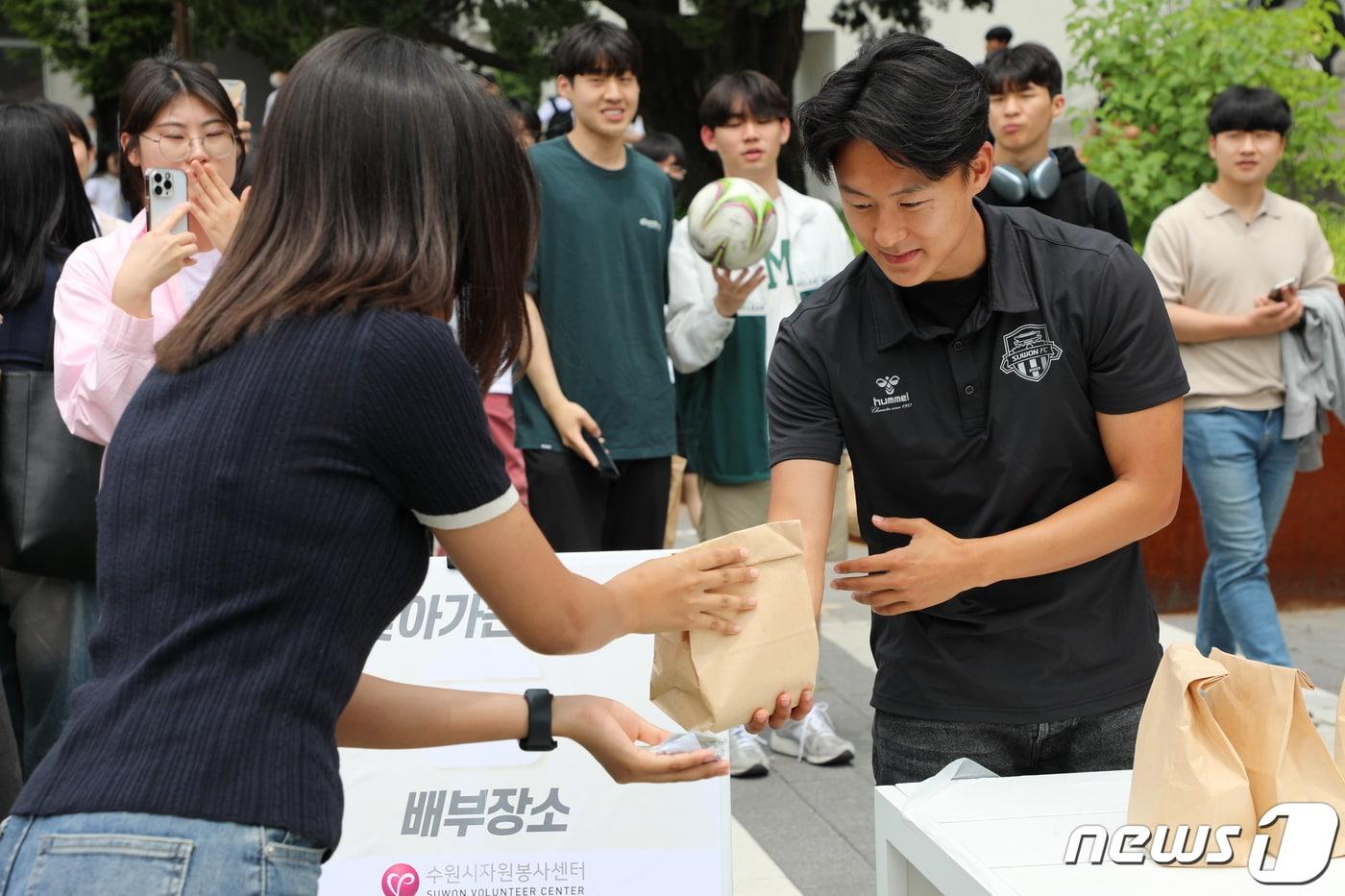 본문 이미지 - 수원FC 소속 이승우 선수가 지난달 8일 기말고사 중인 아주대학교에서 열린 '사랑의 밥차'에서 한 여학생에게 햄버거와 음료수를 건네고 있다.