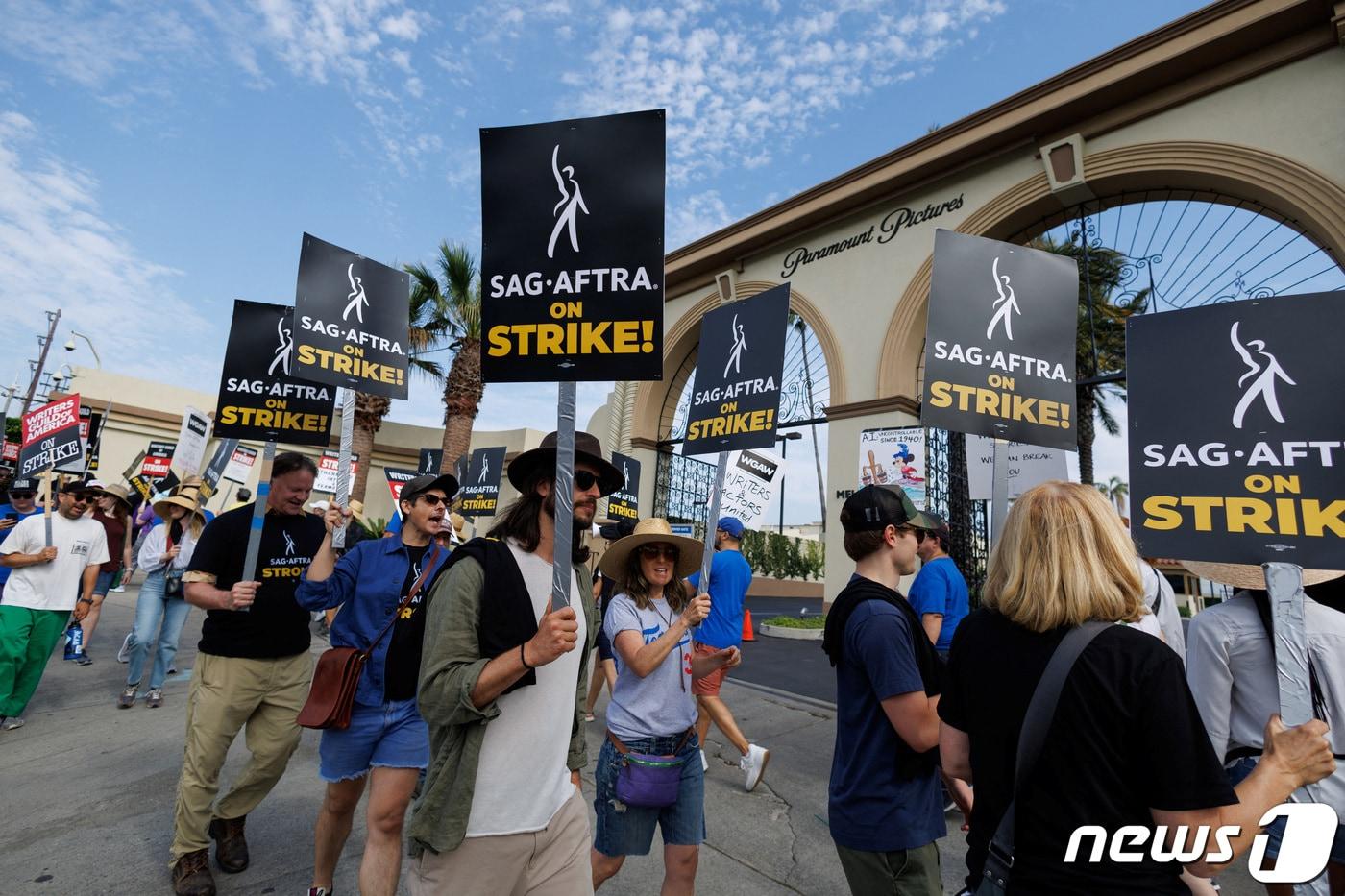 본문 이미지 - 미국 캘리포니아 로스 앤젤레스에 있는 파라마운트 스튜디오 앞에서 파업을 알리는 피켓을 든 배우·작가 조합이 줄지어 가고 있다. 2023.07.18 ⓒ 로이터=뉴스1 ⓒ News1 정지윤 기자