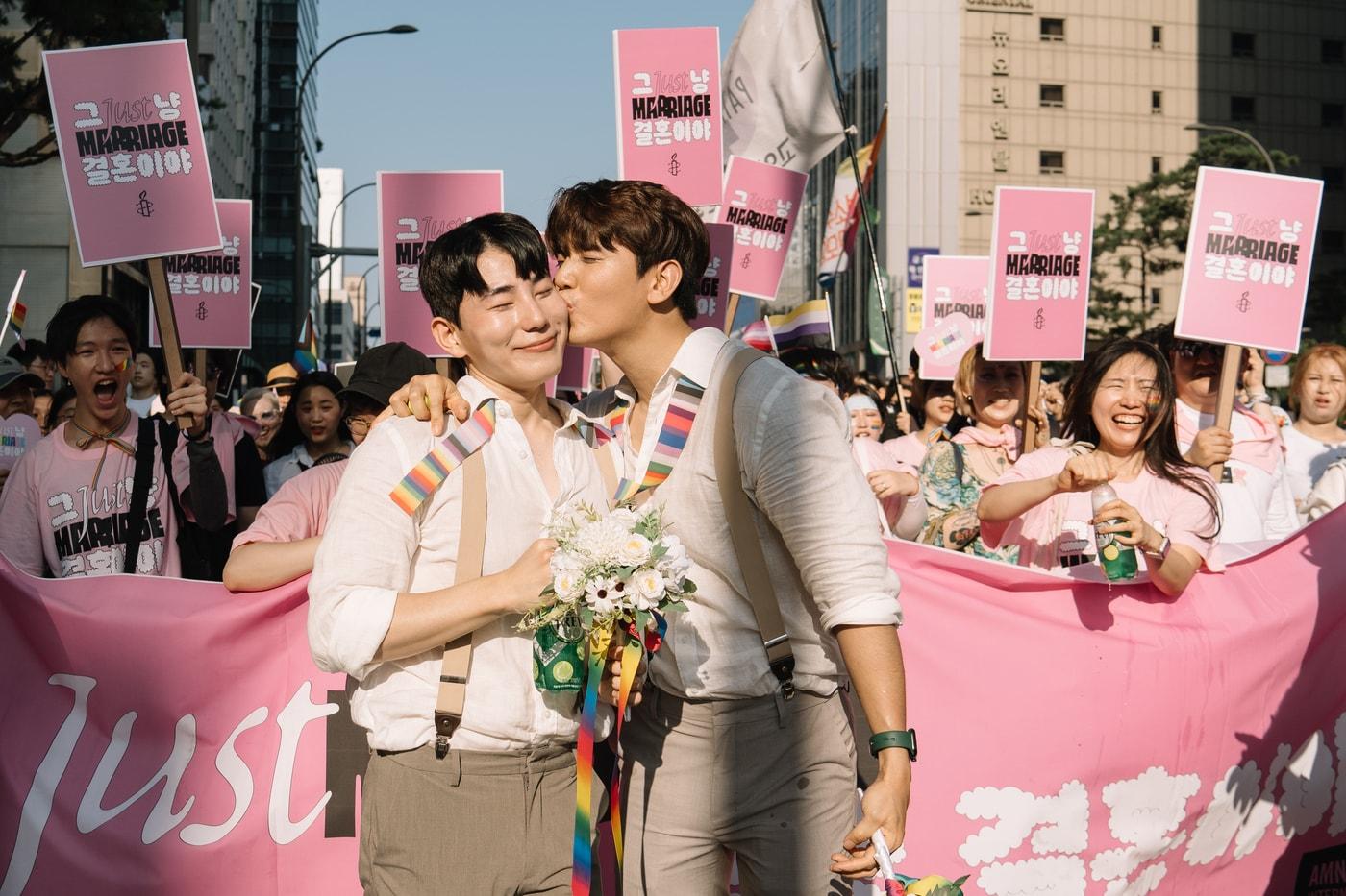 유튜브 채널 망원댁 TV 동성커플 킴(왼쪽)과 백팩(오른쪽)이 1일 오후 서울 중구 삼일대로 일대에서 열린 '제24회 서울퀴어문화축제'에 참가해 국제엠네스티 혼인평등 캠페인 '그냥 결혼이야 (JUST MARRIAGE)' 키스 세리머니를 하고 있다.(국제앰네스티 한국지부 제공) 2023.7.2/뉴스1 ⓒ News1 민경석 기자