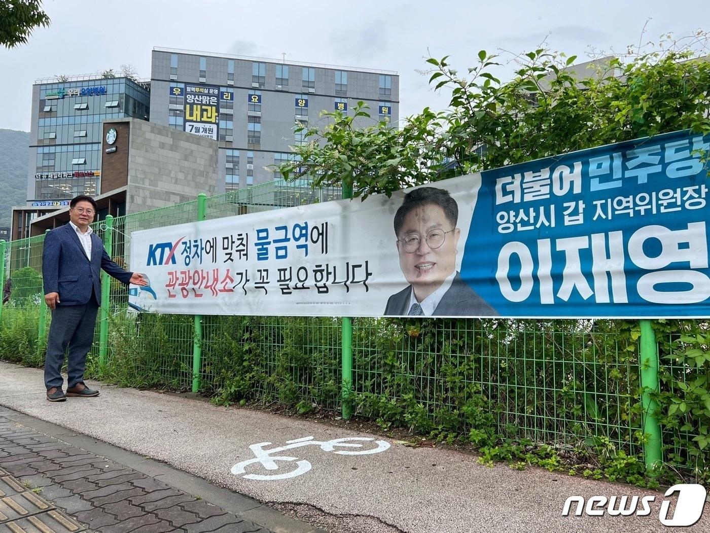 본문 이미지 - 더불어민주당 이재영 양산갑위원장이 KTX 정차예정인 물금역 시 관광안내소 설치를 주장하는 플래카드 앞에 서 있다. (더불어민주당 양산갑지역위원회 제공)