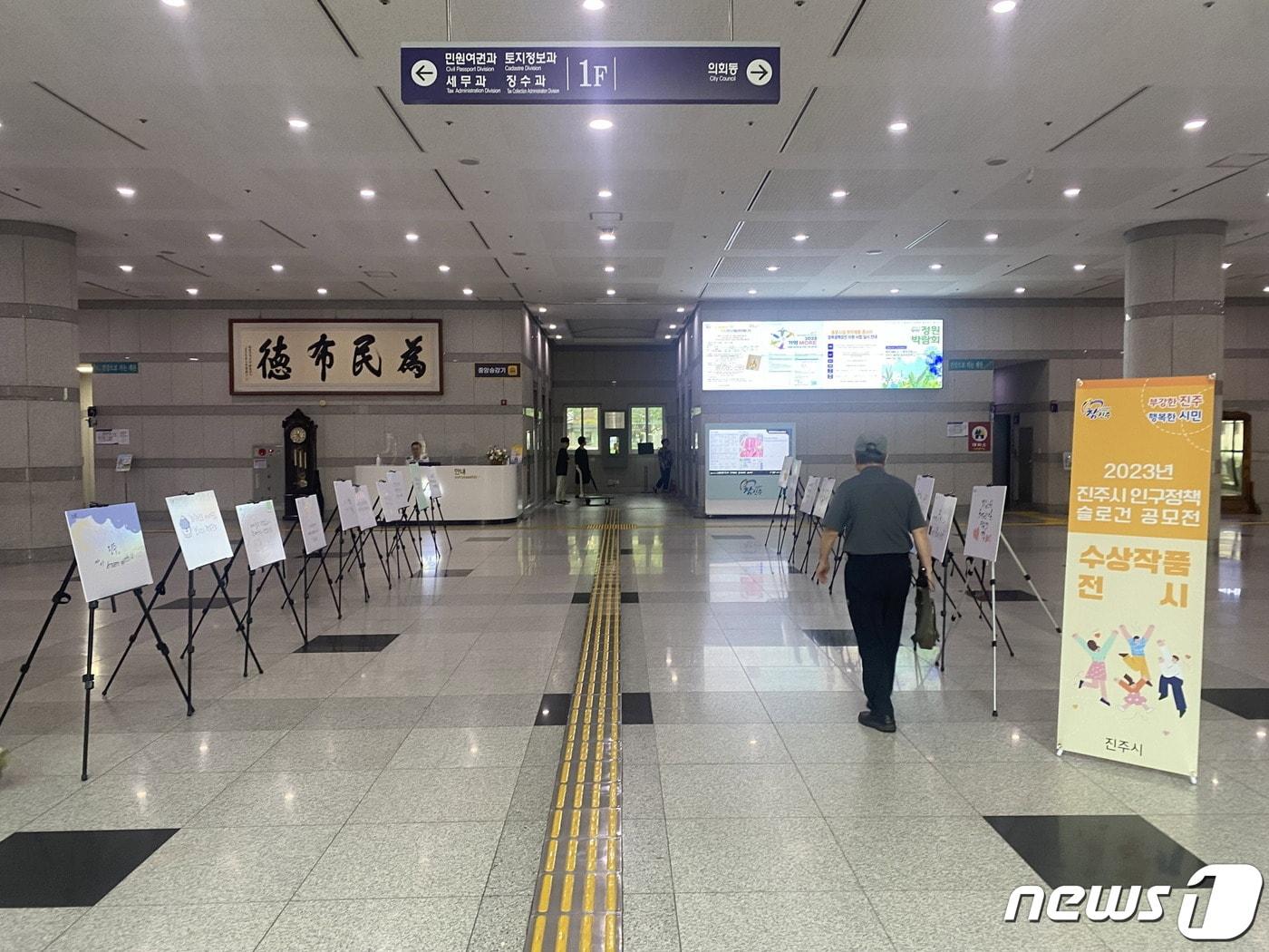 본문 이미지 - 진주시가 지난 7월 10일 2023년 인구정책 슬로건 공모전 수상자들 작품을 시청 로비에 전시하고 있다(진주시 제공).