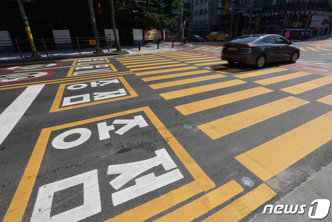 운전자가 어린이보호구역을 쉽게 인식할 수 있도록 노란색 횡단보도가 도입되는 내용의 개정 도로교통법 시행을 하루 앞둔 3일 오후 경기 용인시 기흥구 구갈초등학교 인근 어린이보호구역(스쿨존)에 설치된 노란색 횡단보도 위로 차량이 지나가고 있다. 2023.7.3/뉴스1 ⓒ News1 김영운 기자