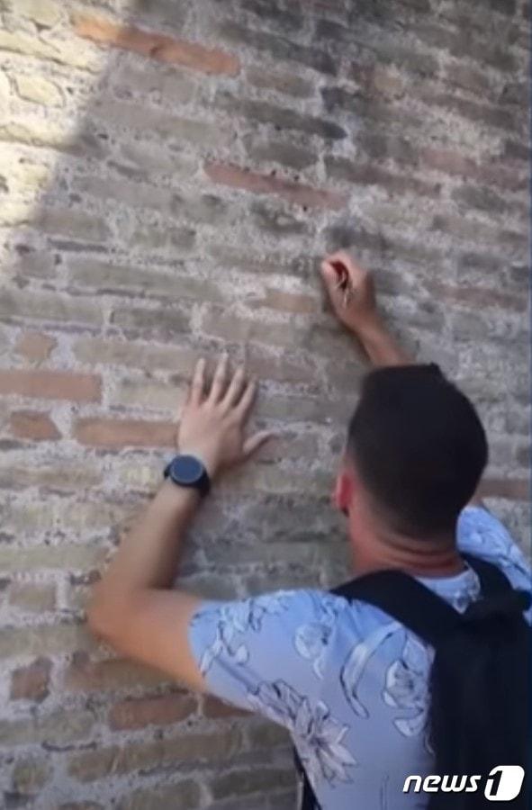 본문 이미지 -  이탈리아 로마의 콜로세움에 자신과 연인의 이름을 새긴 한 남성의 영상이 온라인을 통해 퍼지며 공분을 샀다.(영국 가디언 갈무리).