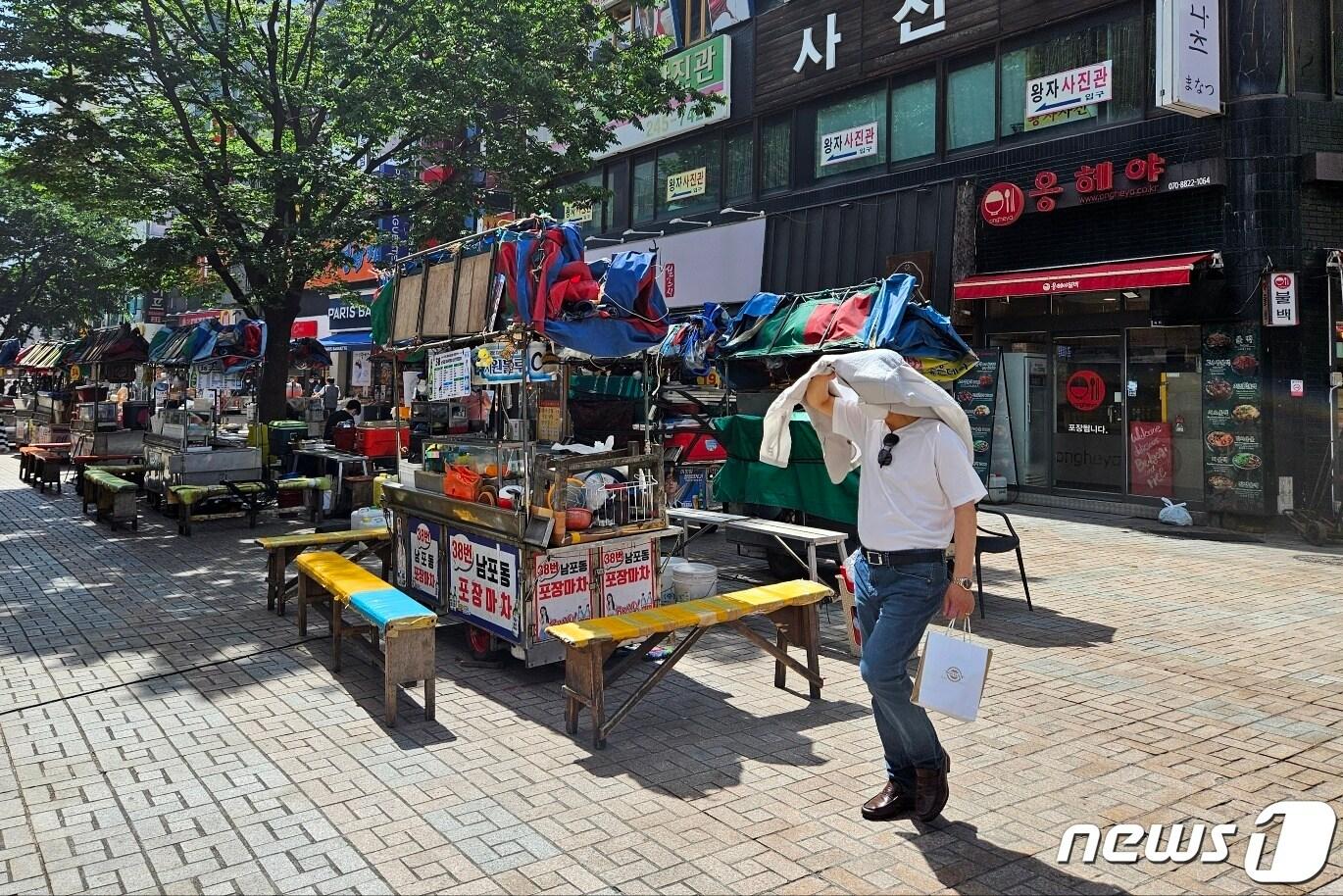 본문 이미지 - 부산 중구 비프광장에서 한 시민이 햇볕을 가리기 위해 겉옷을 벗어 머리에 쓴 채 지나가고 있다. 2023.7.6/뉴스1 ⓒ News1 권영지 기자