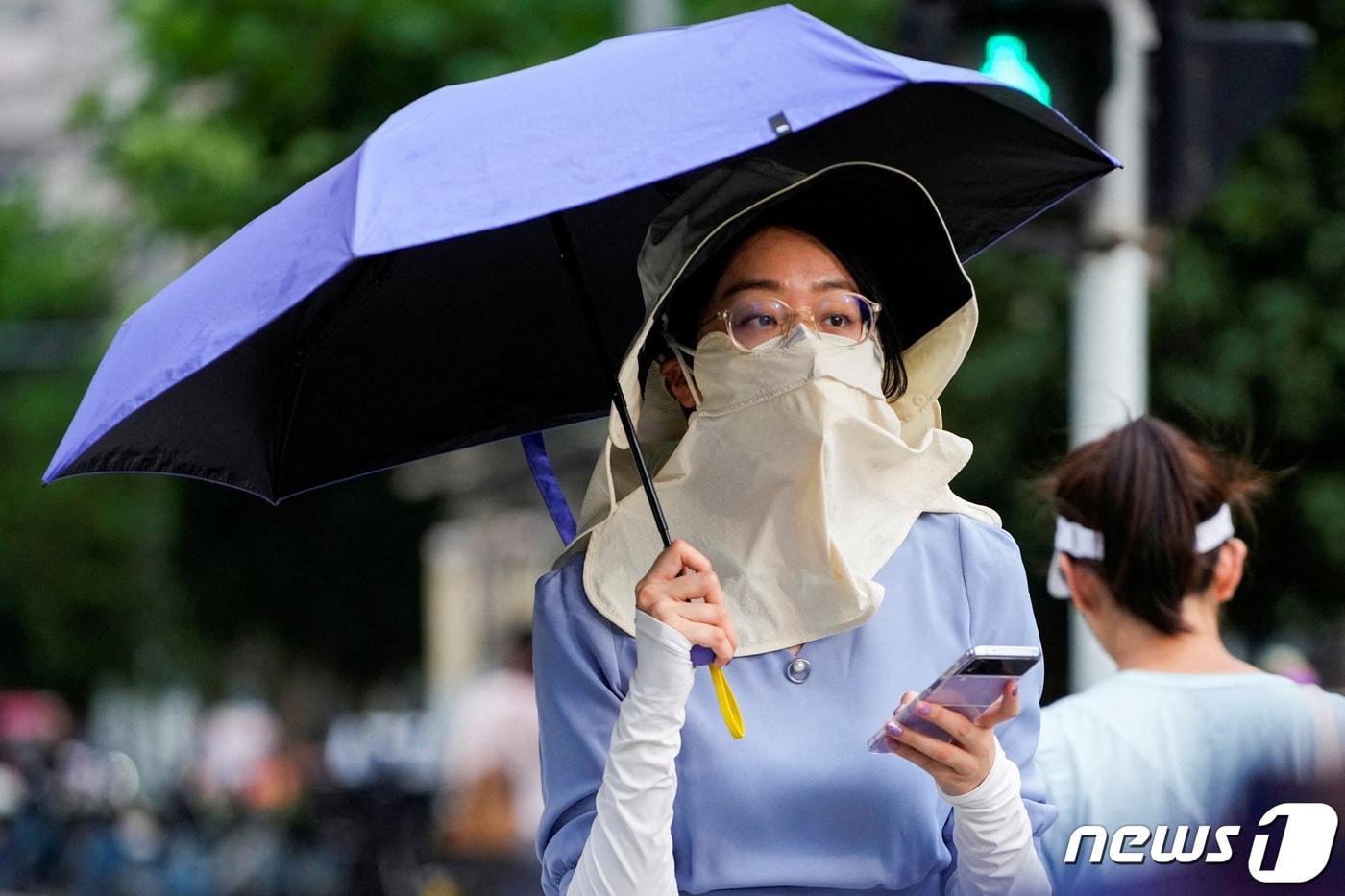 폭염경보가 내려진 중국 상하이에서 한 여성이 모자와 마스크, 우산 등으로 햇빛에 완전 무장하고 길을 걷고 있다. 2023.07.04/ ⓒ 로이터=뉴스1 ⓒ News1 권진영 기자