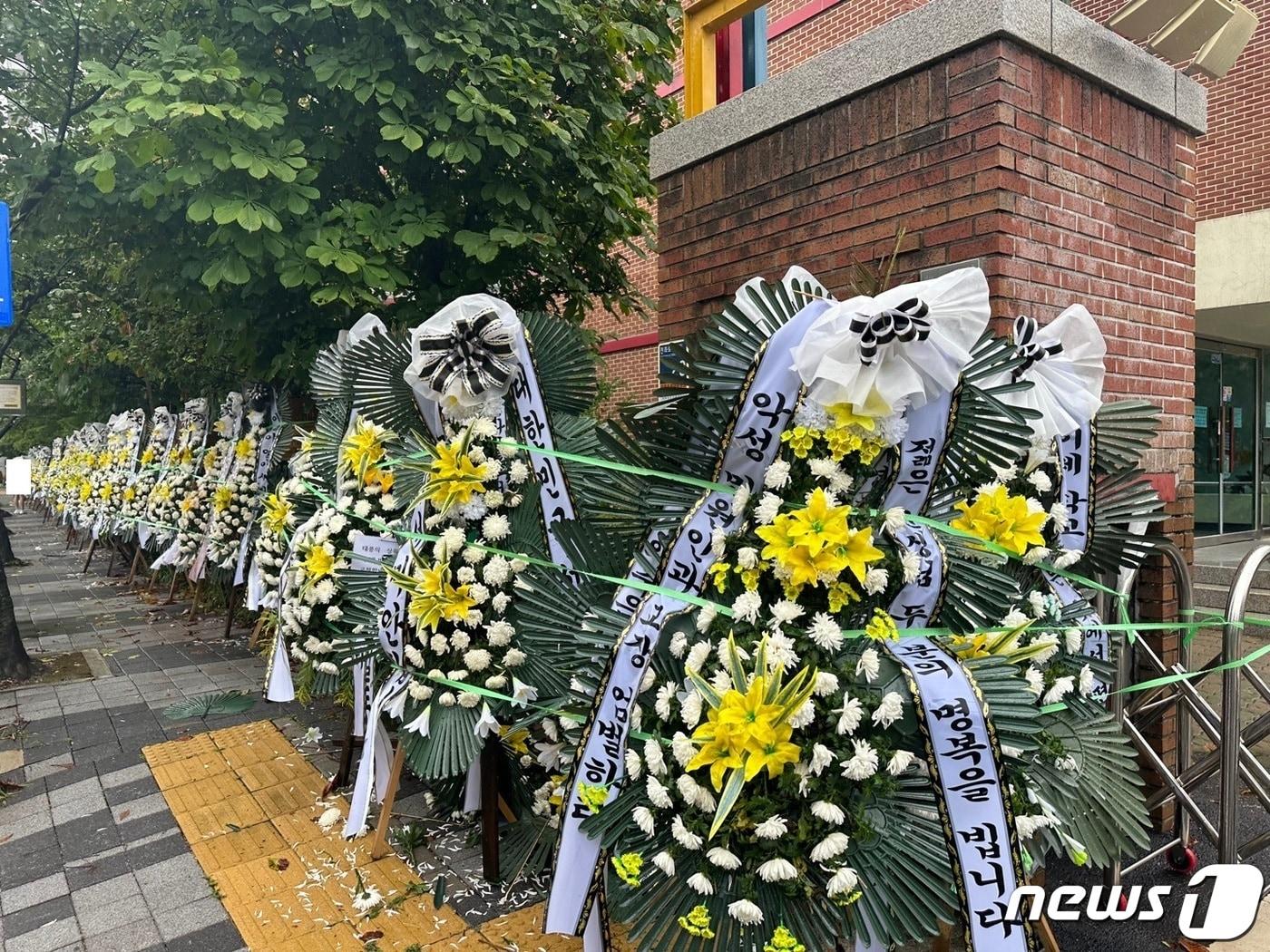 본문 이미지 - 10일 오후 3시50분께 경기 의정부시 호원초등학교 일대에 조화가 줄지어 늘어선 모습. 전국 각지에서 젊은 두 교사의 죽음에 대한 진상규명을 촉구하는 문구를 써서 보냈다. 2023.8.10/뉴스1 ⓒ News1 이상휼 기자
