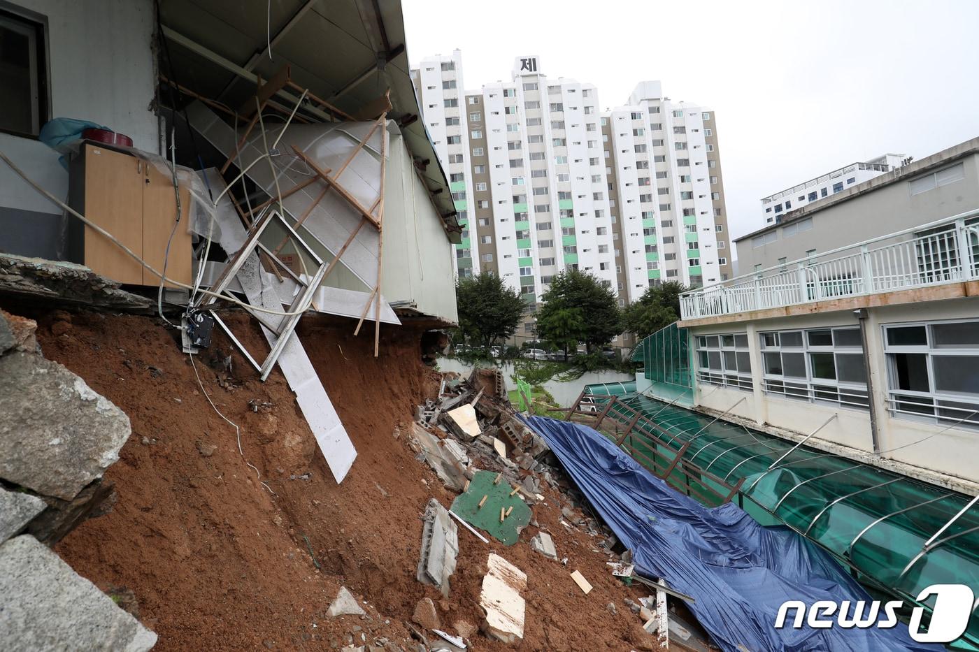 본문 이미지 - 제6호 태풍 '카눈'이 지나간 10일 오후 부산 금정구 금정중학교 인근 공장의 옹벽이 태풍의 영향으로 무너지며 유출된 토사가 학교로 쏟아져 교실 등이 파손돼 있다. 이 학교는 지난달 개학했으나, 태풍 북상에 따라 이날 원격 수업을 진행해 학생 등의 인명 피해는 없었다. 2023.8.10/뉴스1 ⓒ News1 윤일지 기자