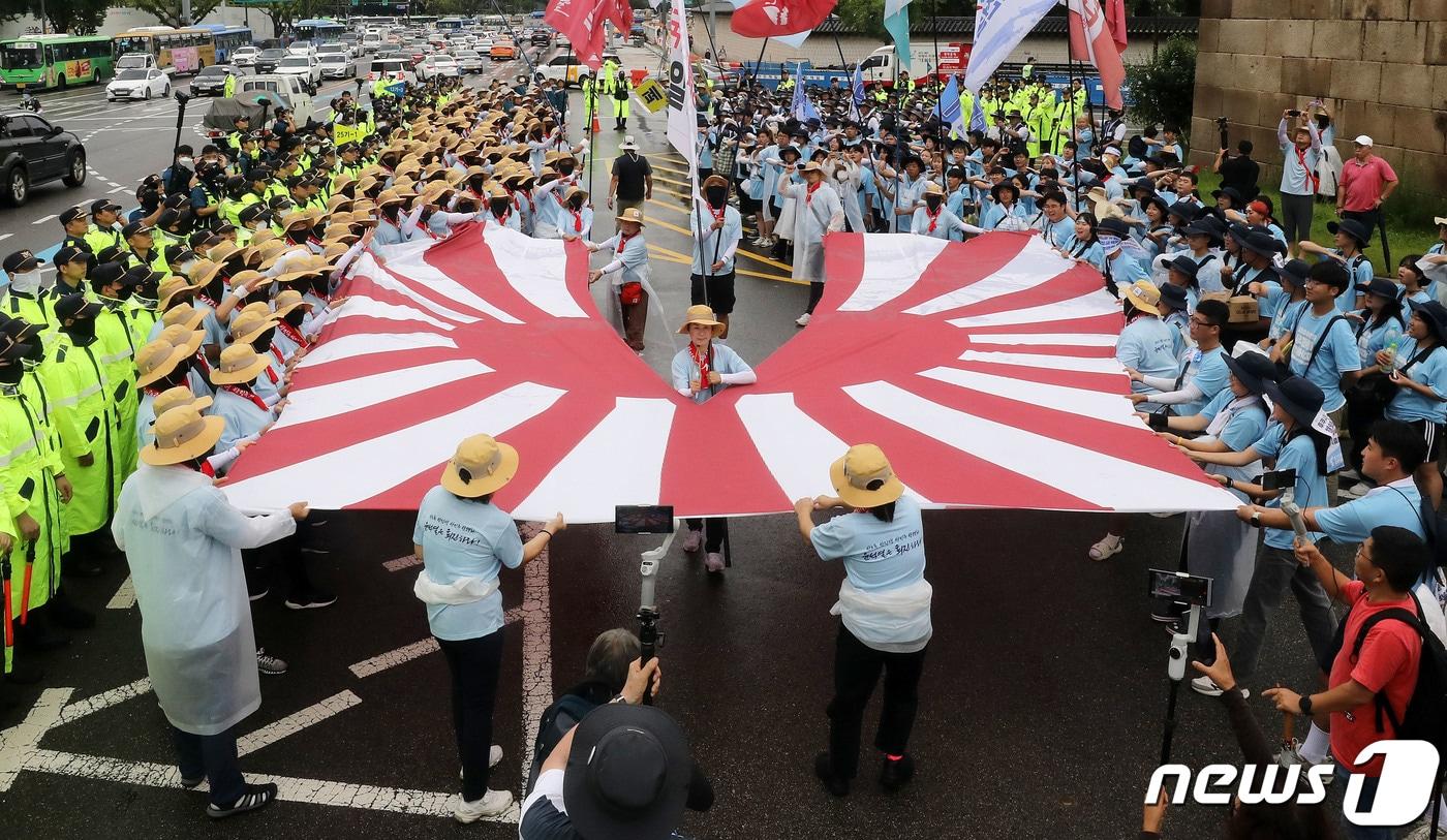 본문 이미지 - 지난해 전국민중행동 통일선봉대 회원들이 서울 종로구 일본대사관 앞에서 ‘핵 오염수 해양투기 반대, 일본대사관 항의 행진’을 마치며 욱일기를 찢는 상징의식을 하고 있다.  ⓒ News1 박세연 기자