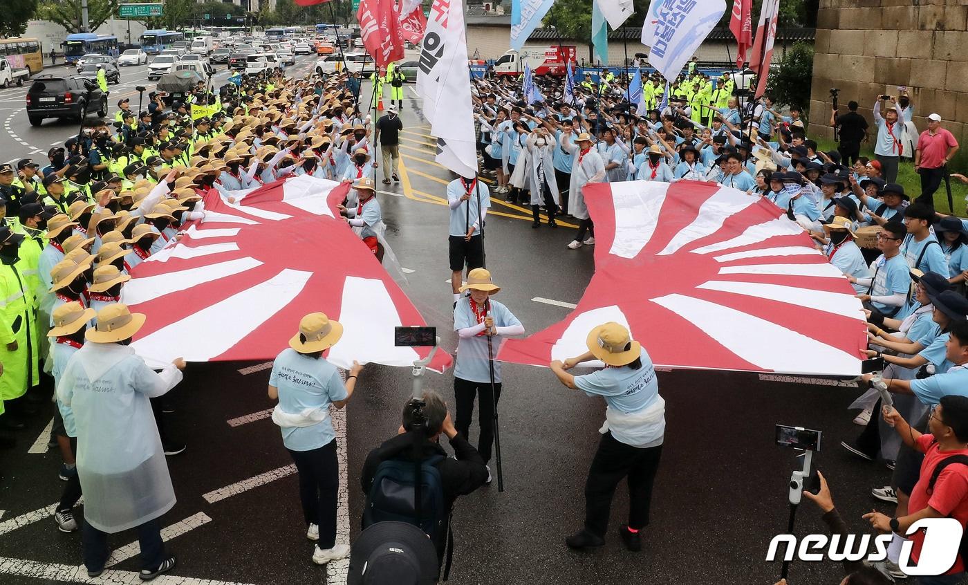 본문 이미지 - 전국민중행동 통일선봉대 회원들이 11일 오후 서울 종로구 일본대사관 앞에서 ‘핵 오염수 해양투기 반대, 일본대사관 항의 행진’을 마치며 욱일기를 찢는 상징의식을 하고 있다. 2023.8.11 ⓒ 뉴스1 박세연 기자
