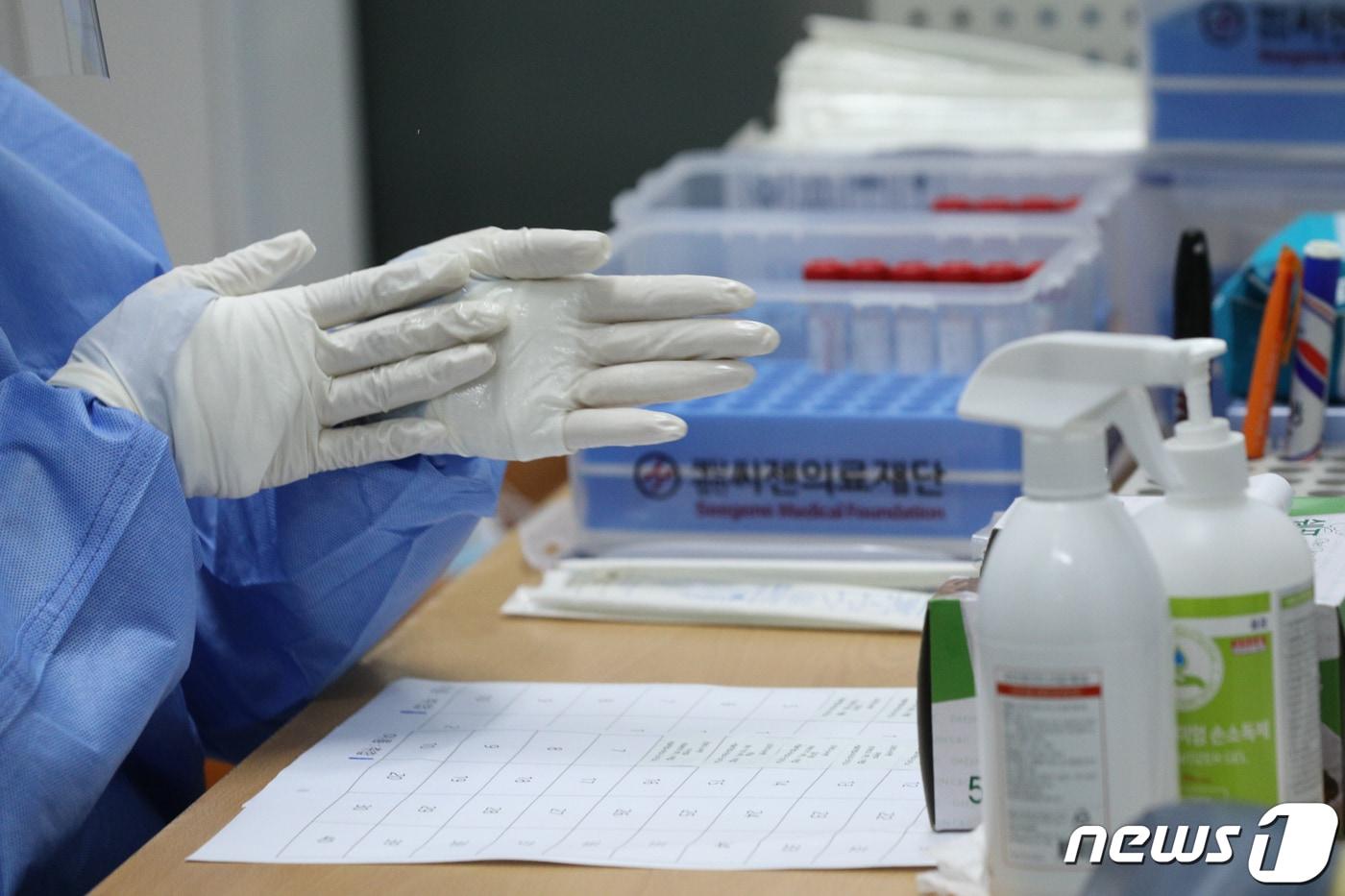 본문 이미지 - 지난 2023년 코로나19 선별진료소에서 의료진이 검체를 채취한 뒤 손을 소독하고 있다. ⓒ 뉴스1  