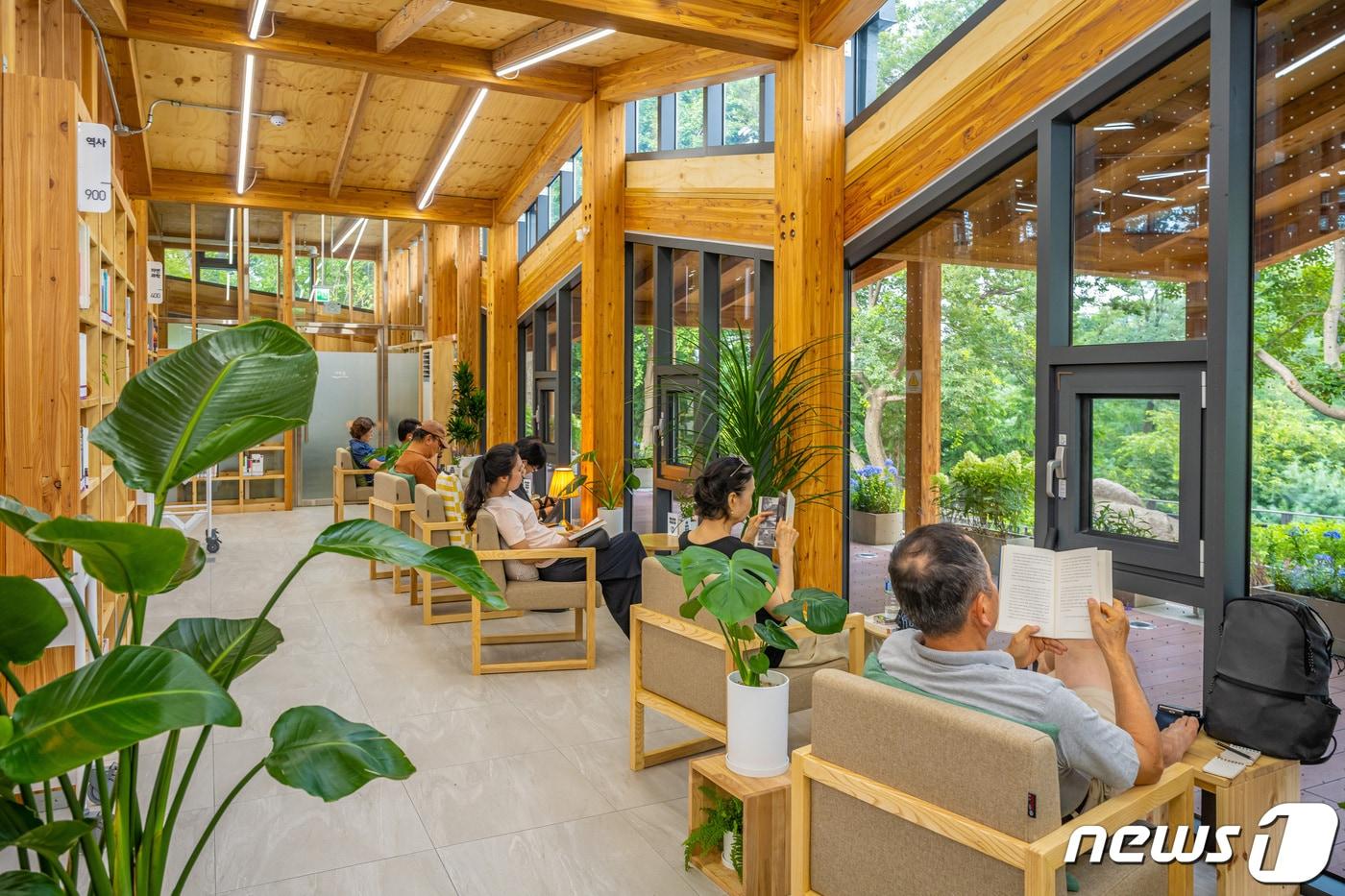 오동숲속도서관에 넓은 창 앞에 마련된 독서공간에서 책을 읽고 있는 사람들(서울관광재단 제공)