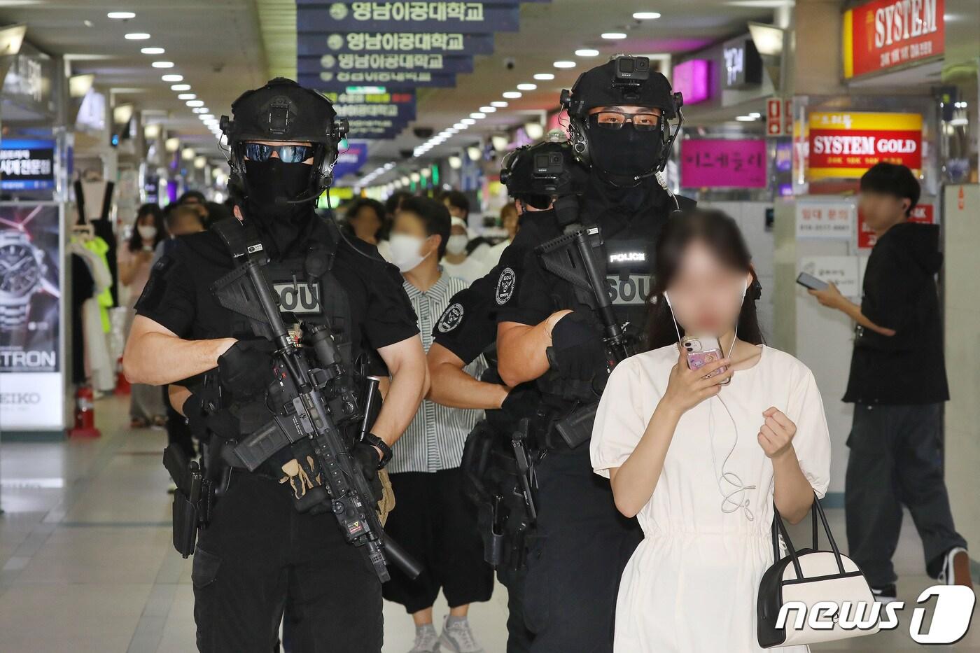 6일 오후 흉기 난동 등 범죄 예방을 위해 대구 중구 동성로~중앙로 구간에 배치된 경찰특공대가 지하상가 등 다중이용시설에 대한 순찰을 강화한 가운데 귀에 이어폰을 꽂은 한 여성이 경찰특공대 인기척을 느끼지 못한 채 걷고 있다. 2023.8.6/뉴스1 ⓒ News1 공정식 기자