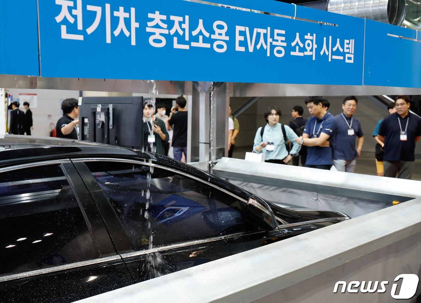 본문 이미지 - 대한민국 안전산업박람회를 찾은 관람객들이 필슨(FILTSON)의 전기차 충전소용 EV자동 소화 시스템에 대한 설명을 듣고 있다. 2023.9.13/뉴스1 ⓒ News1 안은나 기자