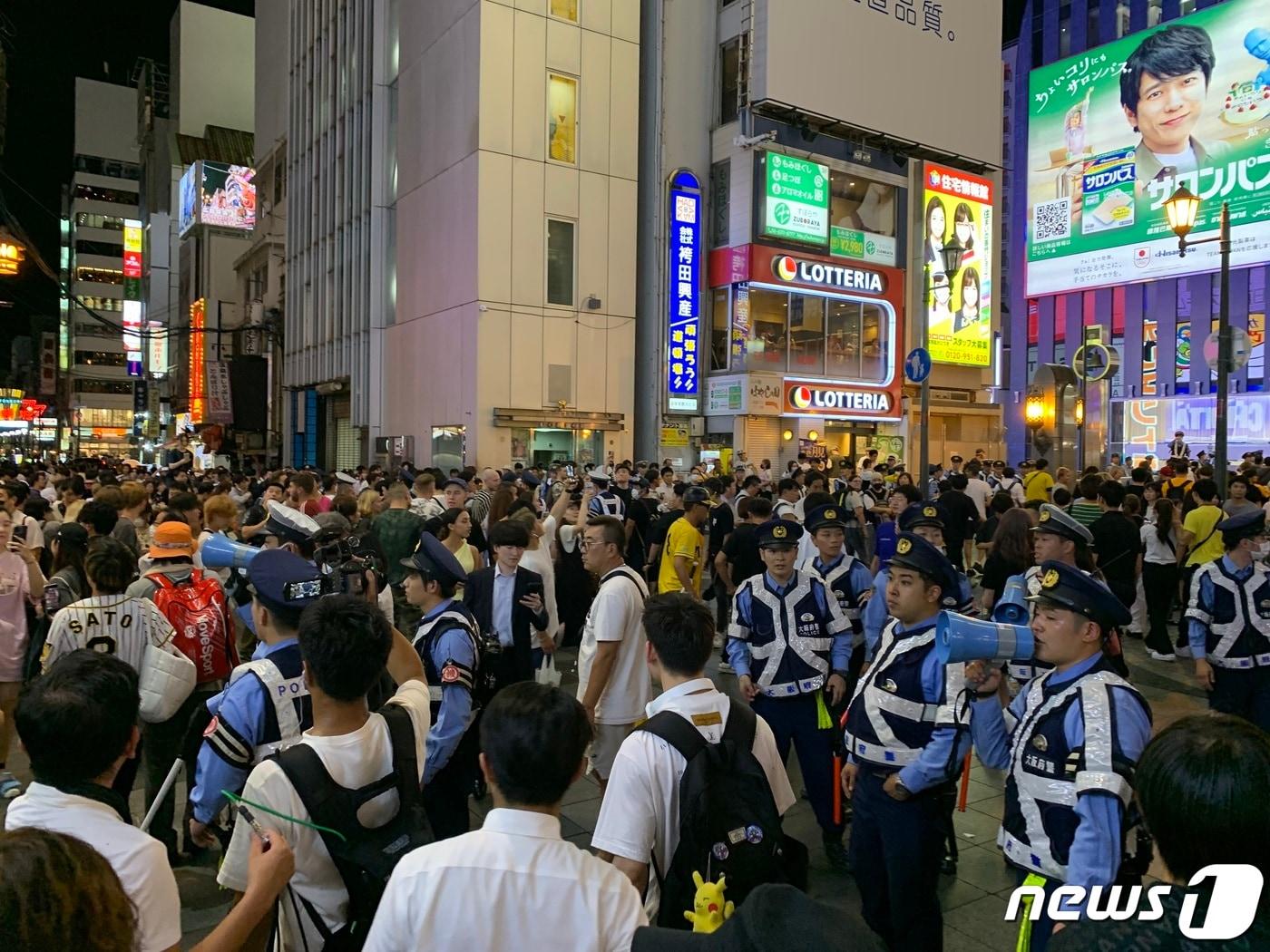 본문 이미지 - 한신 타이거즈가 18년 만에 센트럴리그 정규시즌 우승을 확정지은 14일 밤 일본 오사카 도톤보리강 일대에서 경찰이 관광객과 야구팬들의 질서유지 협력을 당부하고 있다. 일본 경찰은 이날 오사카 대표 관광지인 도톤보리강 주위로 차량 수십대와 인력을 배치해 압사 및 입수 사고에 대비했다. 2023.9.14/뉴스1 ⓒ News1 박정호 기자