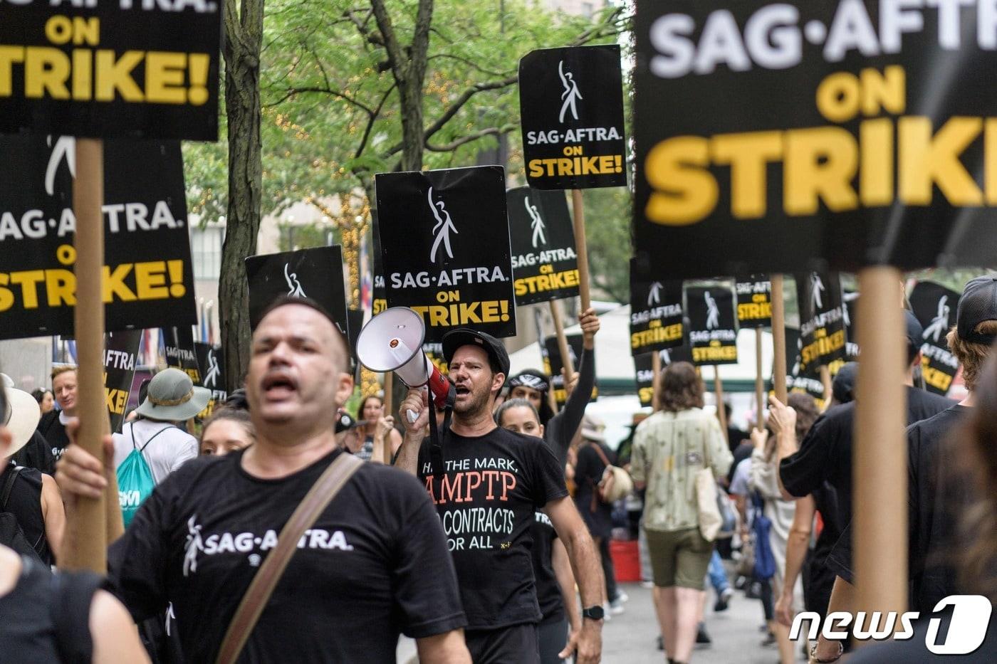 본문 이미지 - 지난 7월19일(현지시간) 미국작가조합(WGA)의 파업에 합류한 미국배우·방송인노동조합(SAG·AFTRA) 조합원들이 미국 뉴욕에서 손팻말을 들고 거리를 행진하고 있다.2023.9.25. ⓒ AFP=뉴스1 ⓒ News1 김기성 기자