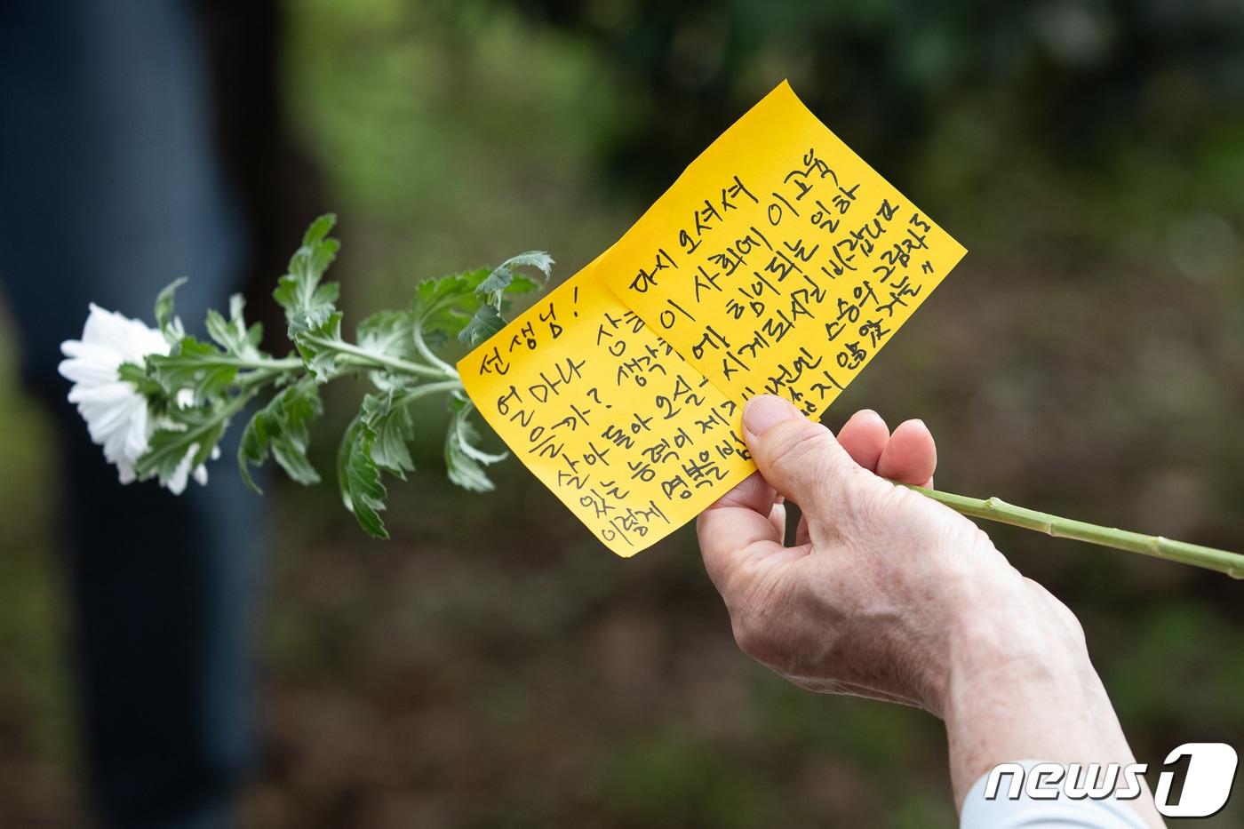 서울 서이초 사망 교사의 49재인 4일 서울 서초구 서이초등학교에 마련된 추모공간을 찾은 한 추모객의 손에 국화와 추모문구가 들려 있다. 2023.9.4/뉴스1 ⓒ News1 유승관 기자