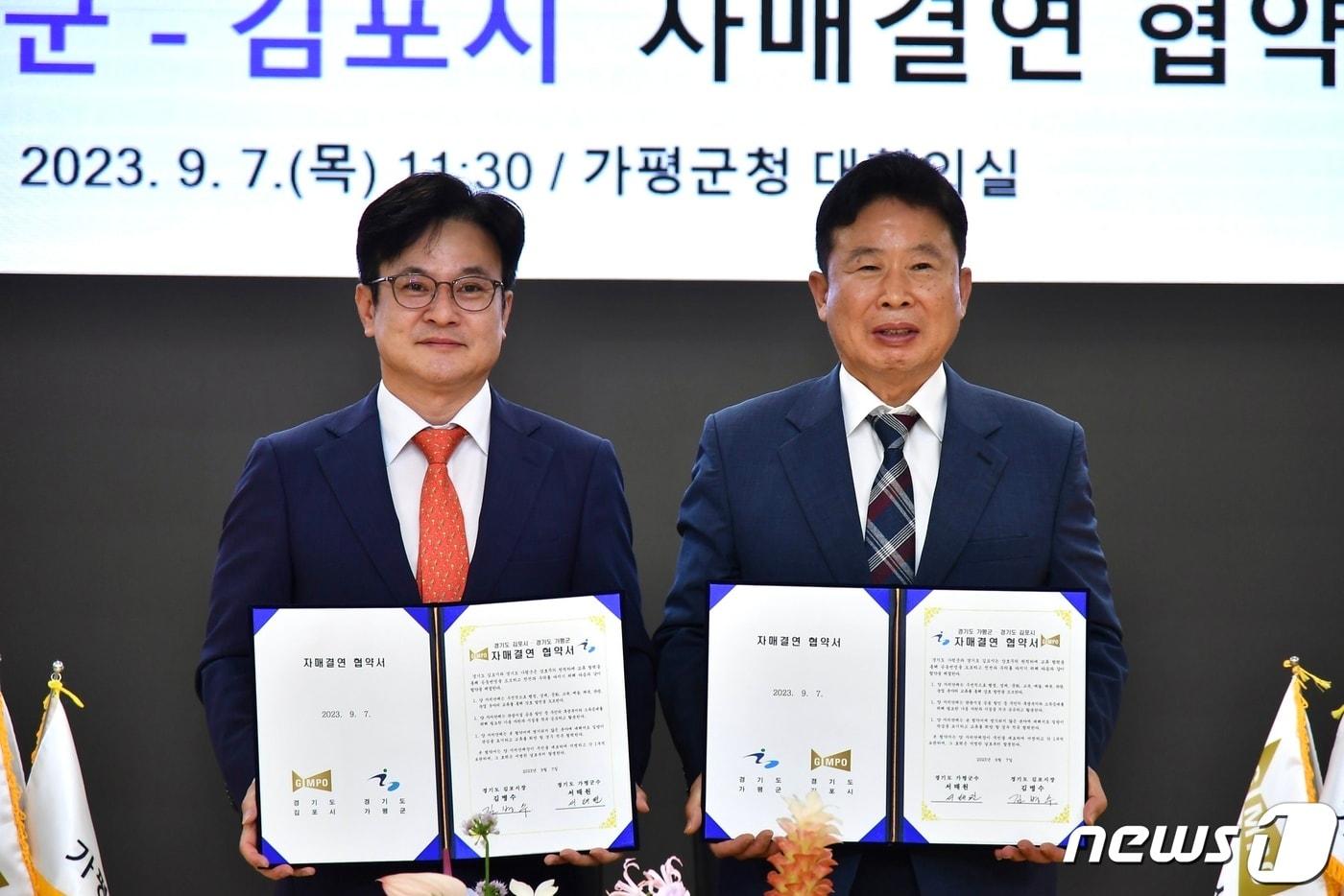 본문 이미지 - 김병수 김포시장(왼쪽)과 서태원 가평군수(오른쪽)가 협약서에 서명 후 기념사진을 촬영하고 있다.(김포시 제공) / 뉴스1