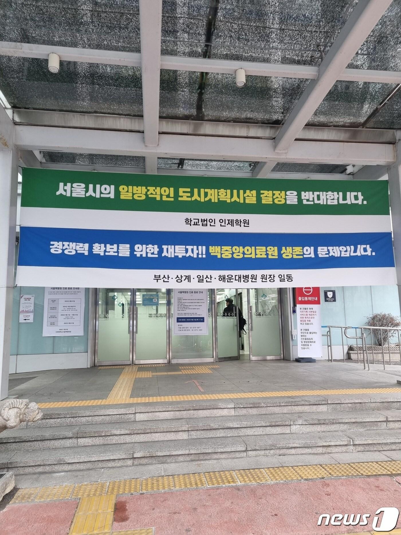 본문 이미지 - 11일 오후 서울백병원 백인제홀에서 도시관리계획(종합의료시설) 결정안에 대한 주민설명회가 열렸다. 병원 입구에 반대 현수막이 걸려 있다.  